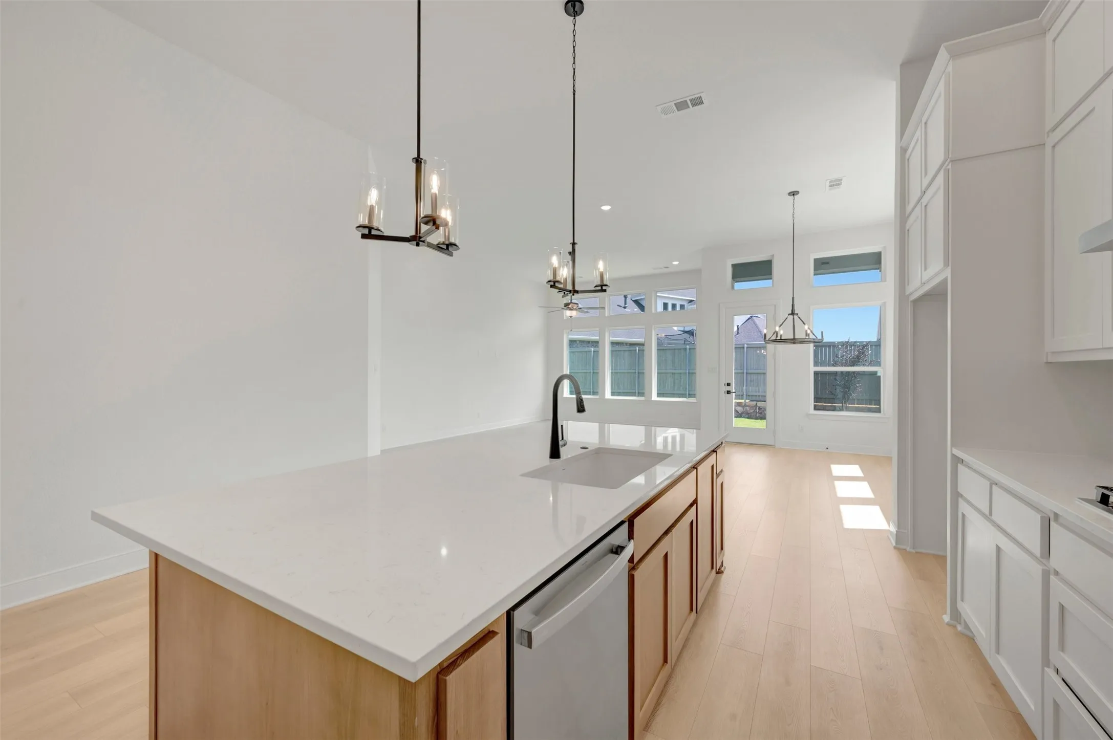 Kitchen island featuring a white countertop, undermount sink, and wood-finish cabinetry