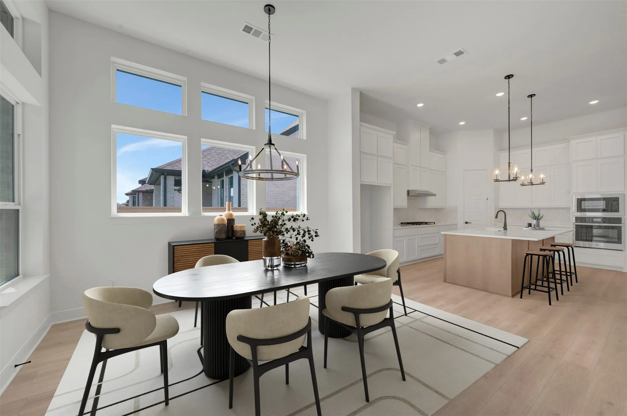 Open-concept living space featuring high ceilings, light wood-finish flooring, and abundant natural light