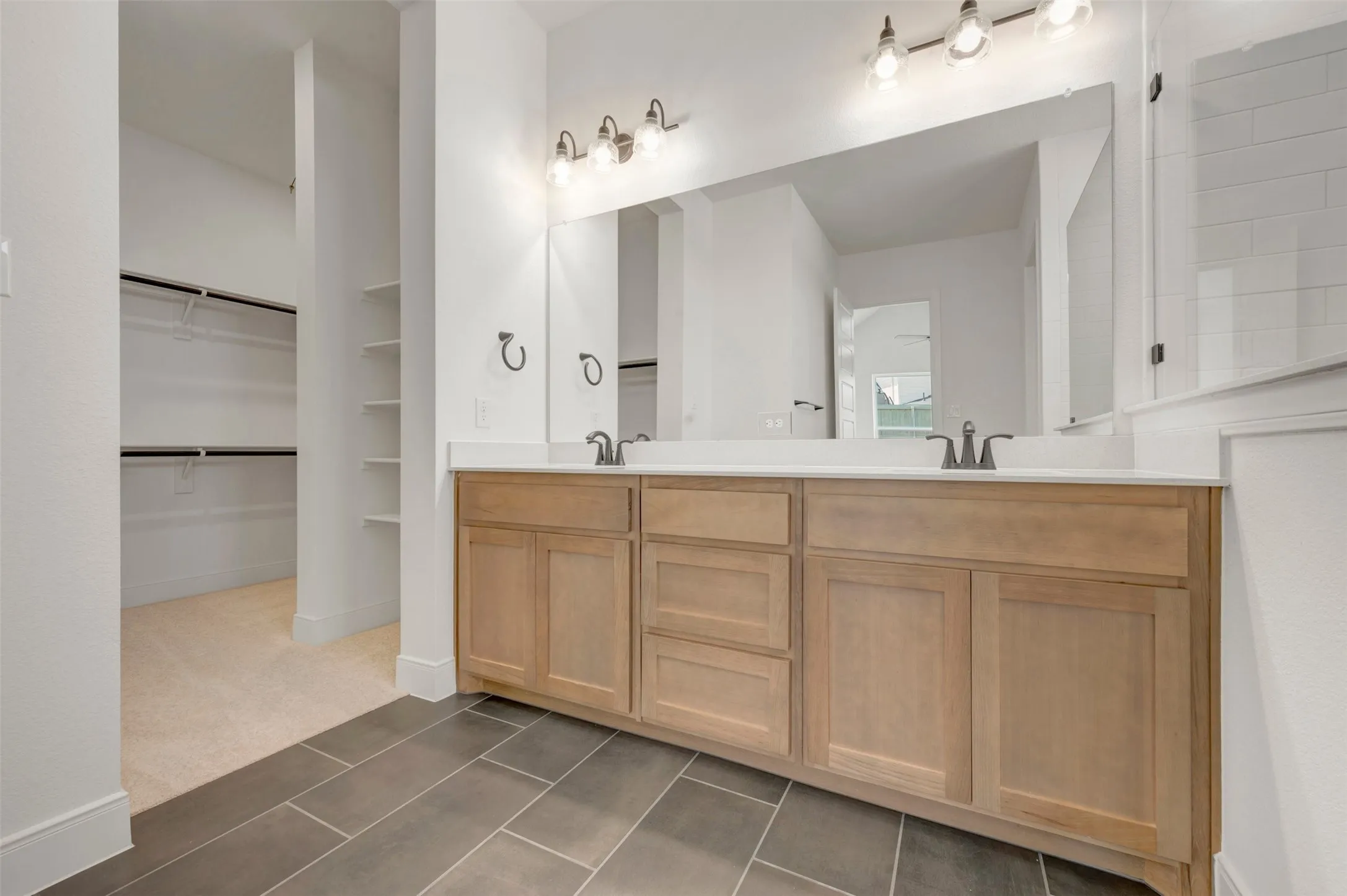 Dual vanity with light wood-finish cabinetry and white countertops