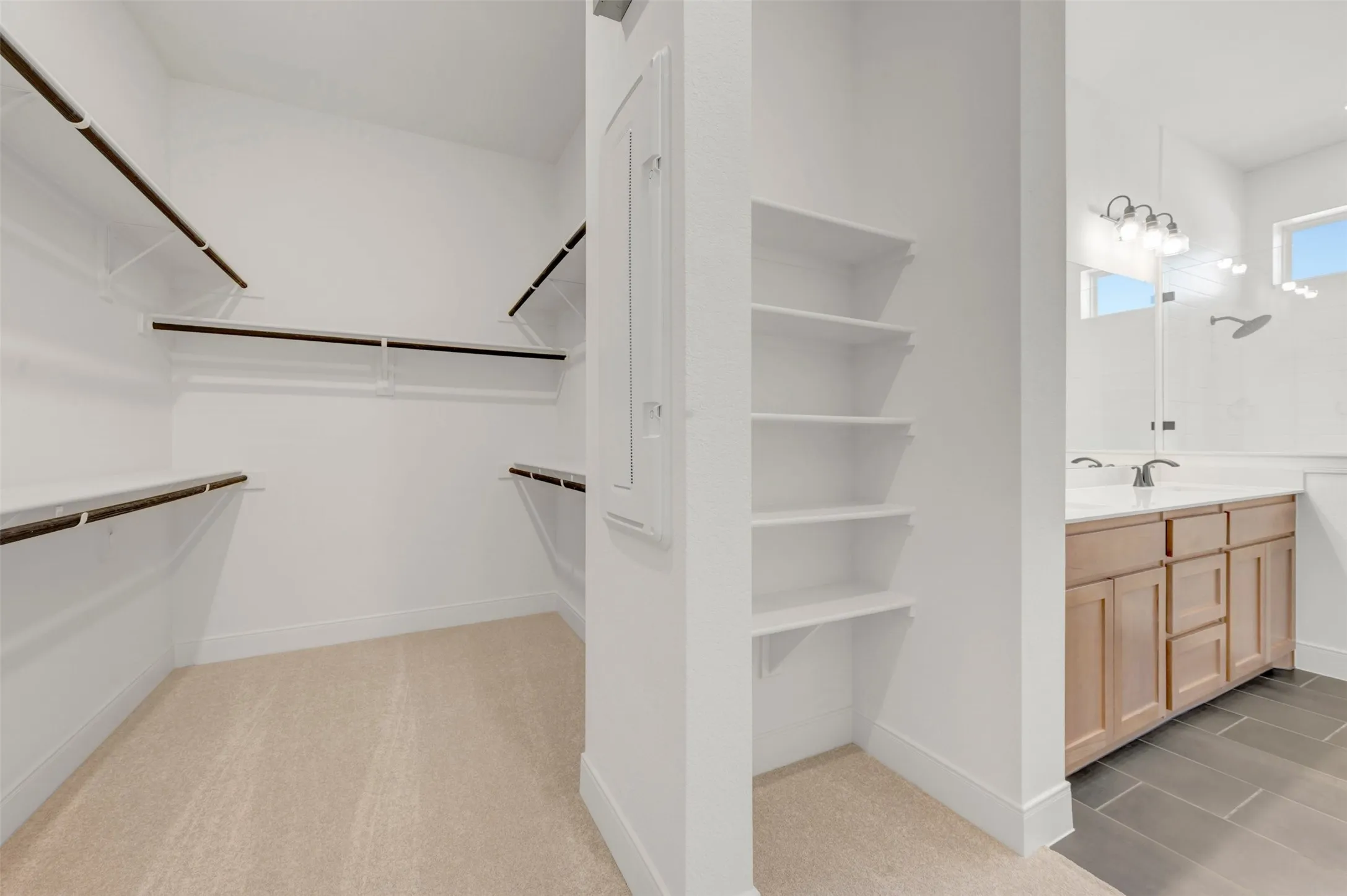 Walk-in closet featuring carpet flooring, built-in shelving, and hanging rods