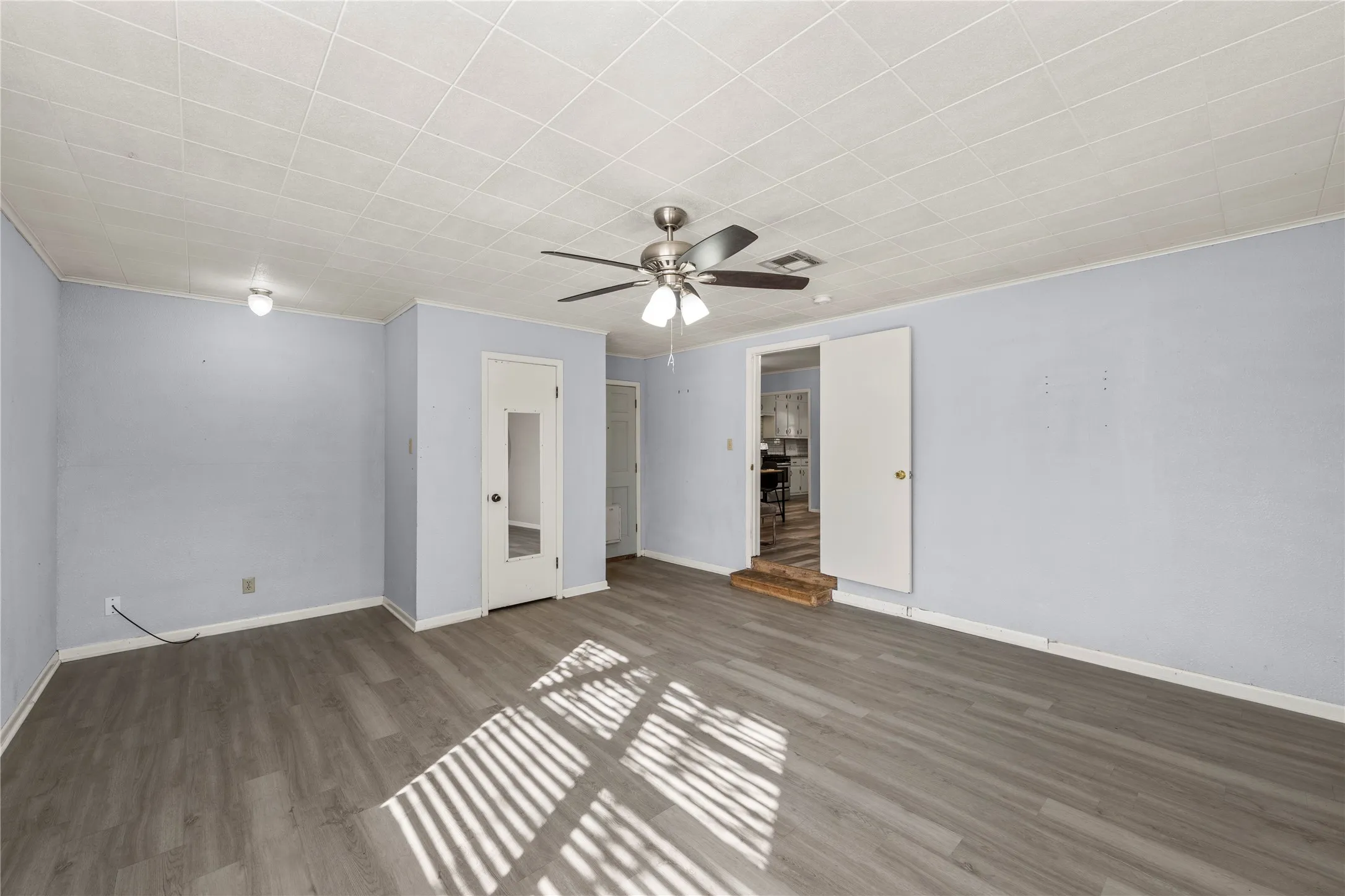 Unfurnished bedroom with dark wood-type flooring, ornamental molding, and a ceiling fan
