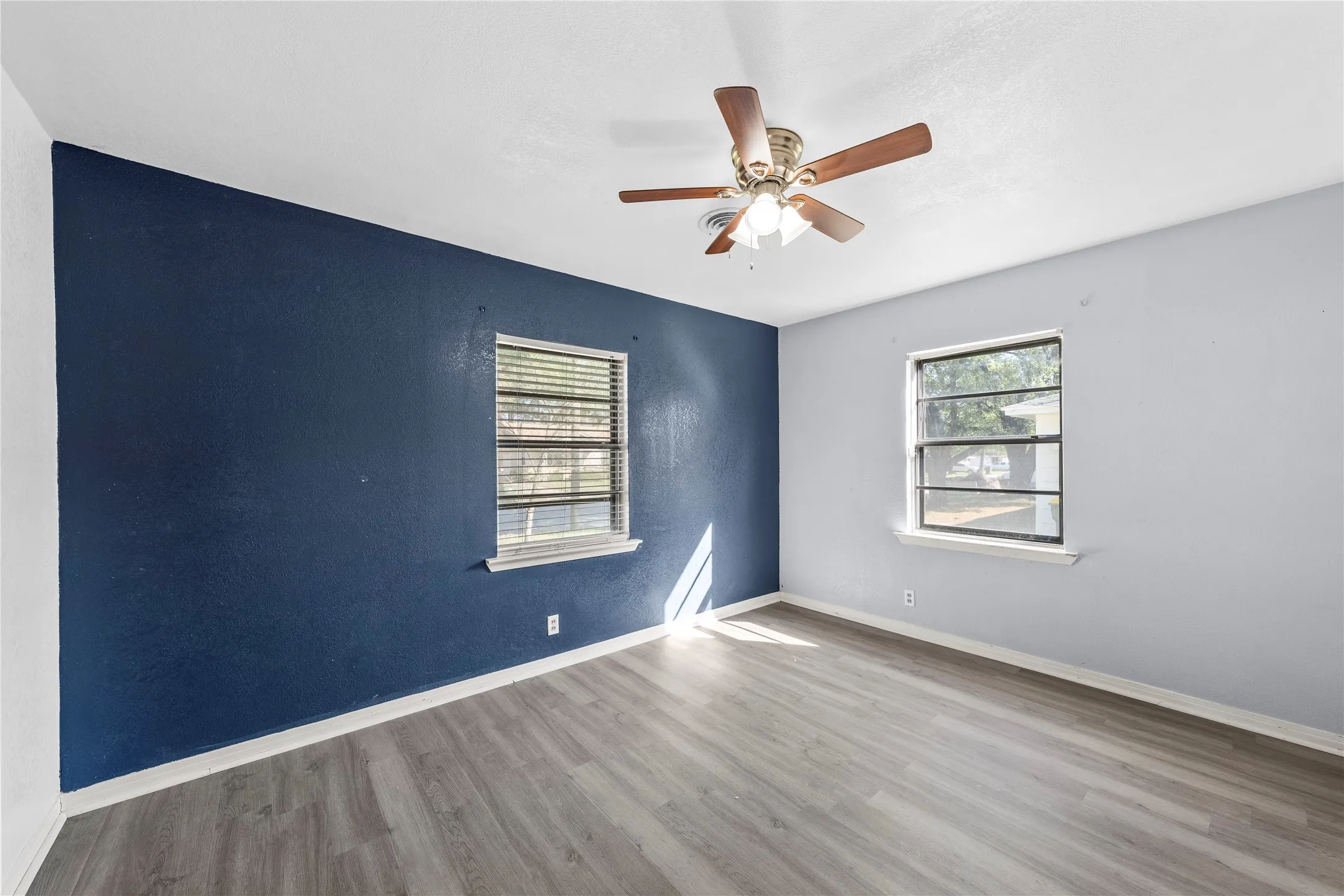 Unfurnished room with light wood finished floors, plenty of natural light, and ceiling fan