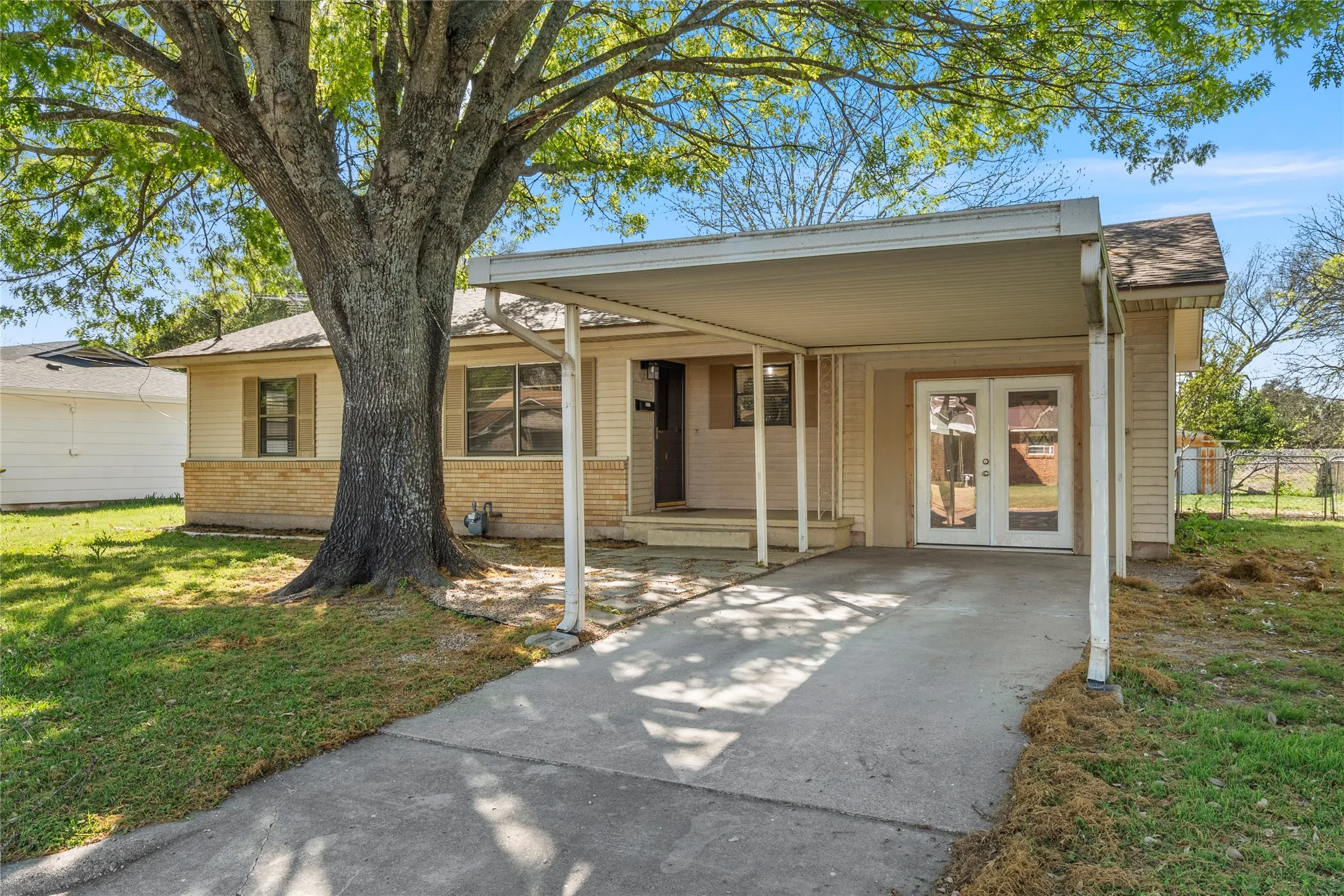 View of front facade featuring a carport, driveway, french doors, and a front lawn