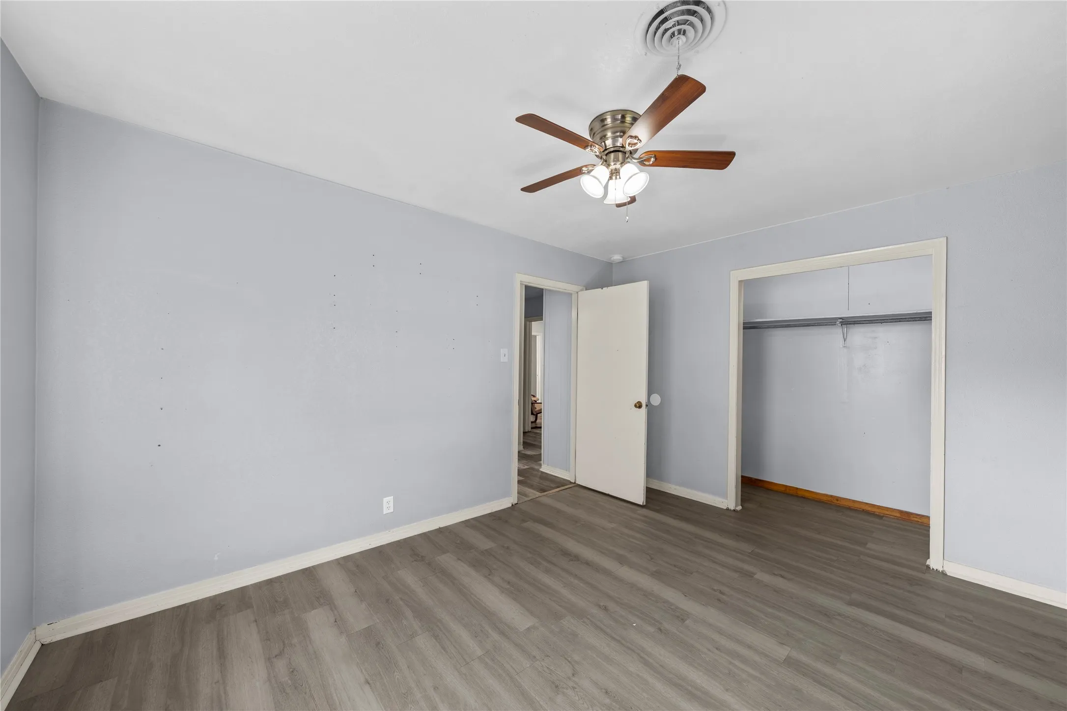 Unfurnished bedroom featuring wood finished floors, ceiling fan, and a closet