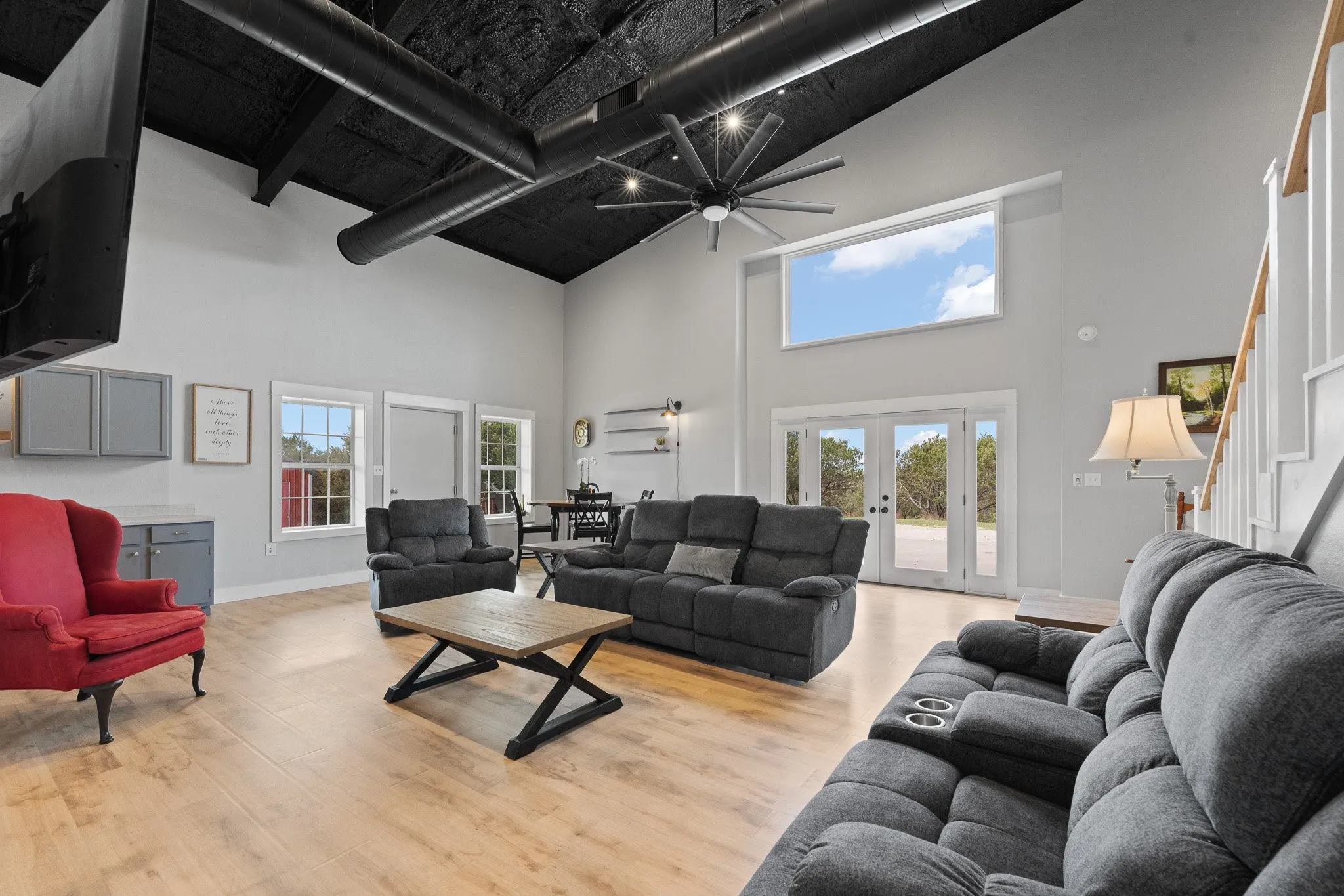 Living area featuring light wood-style floors, french doors, ceiling fan, and vaulted ceiling