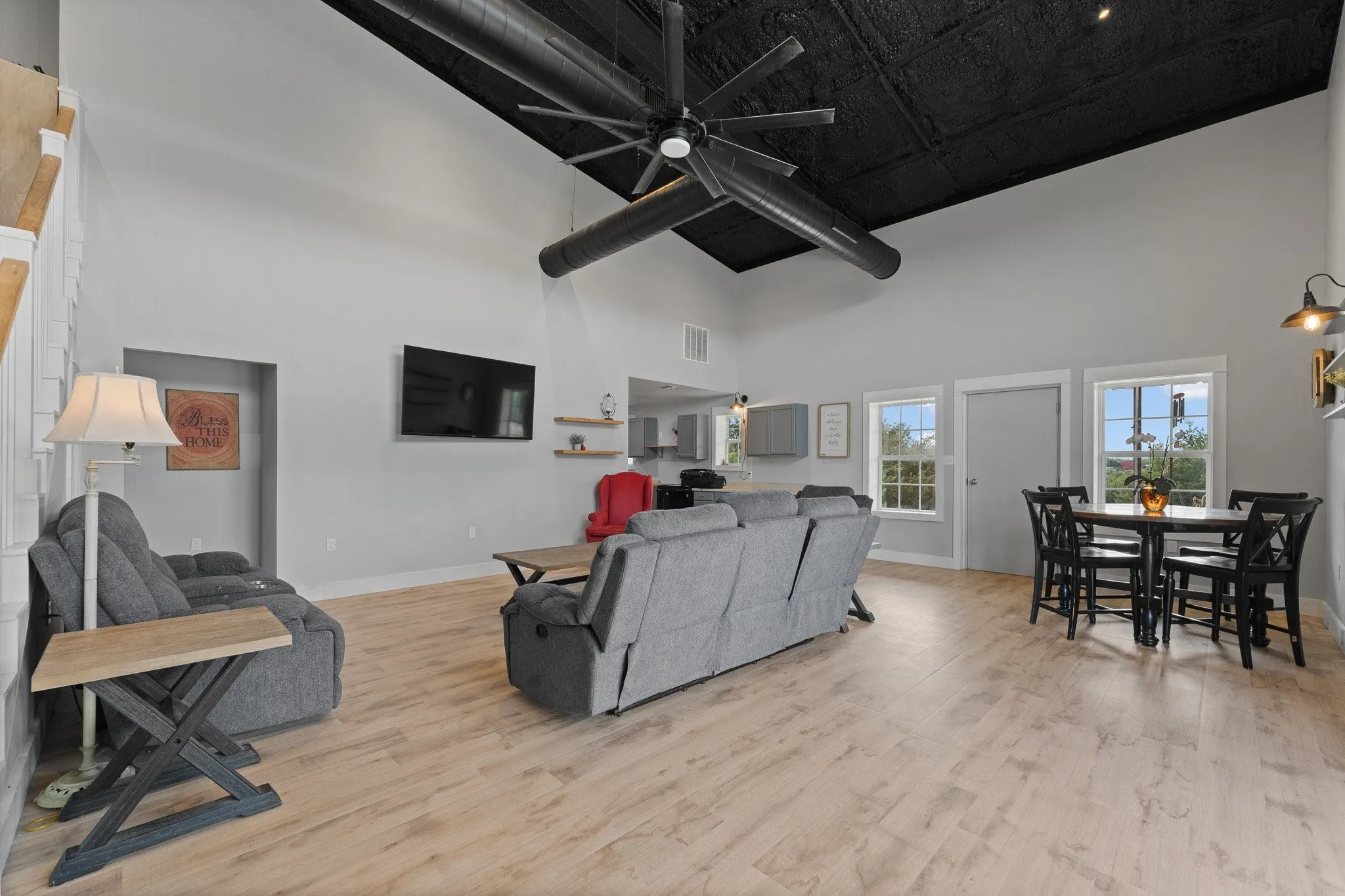 Living area featuring ceiling fan, light wood-style floors, and a high ceiling