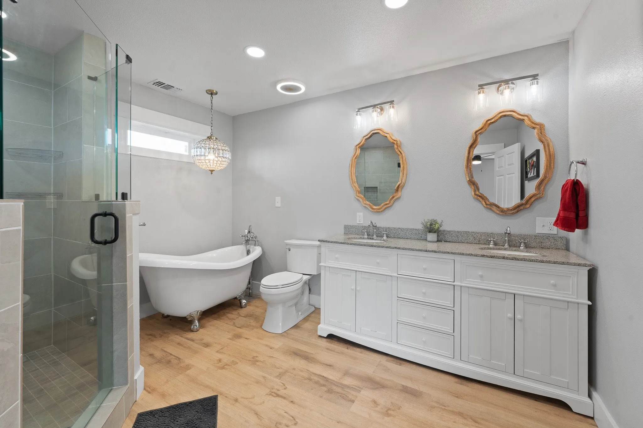 Primary bath featuring a soaking tub, double vanity, a stall shower, light wood-style floors, and recessed lighting
