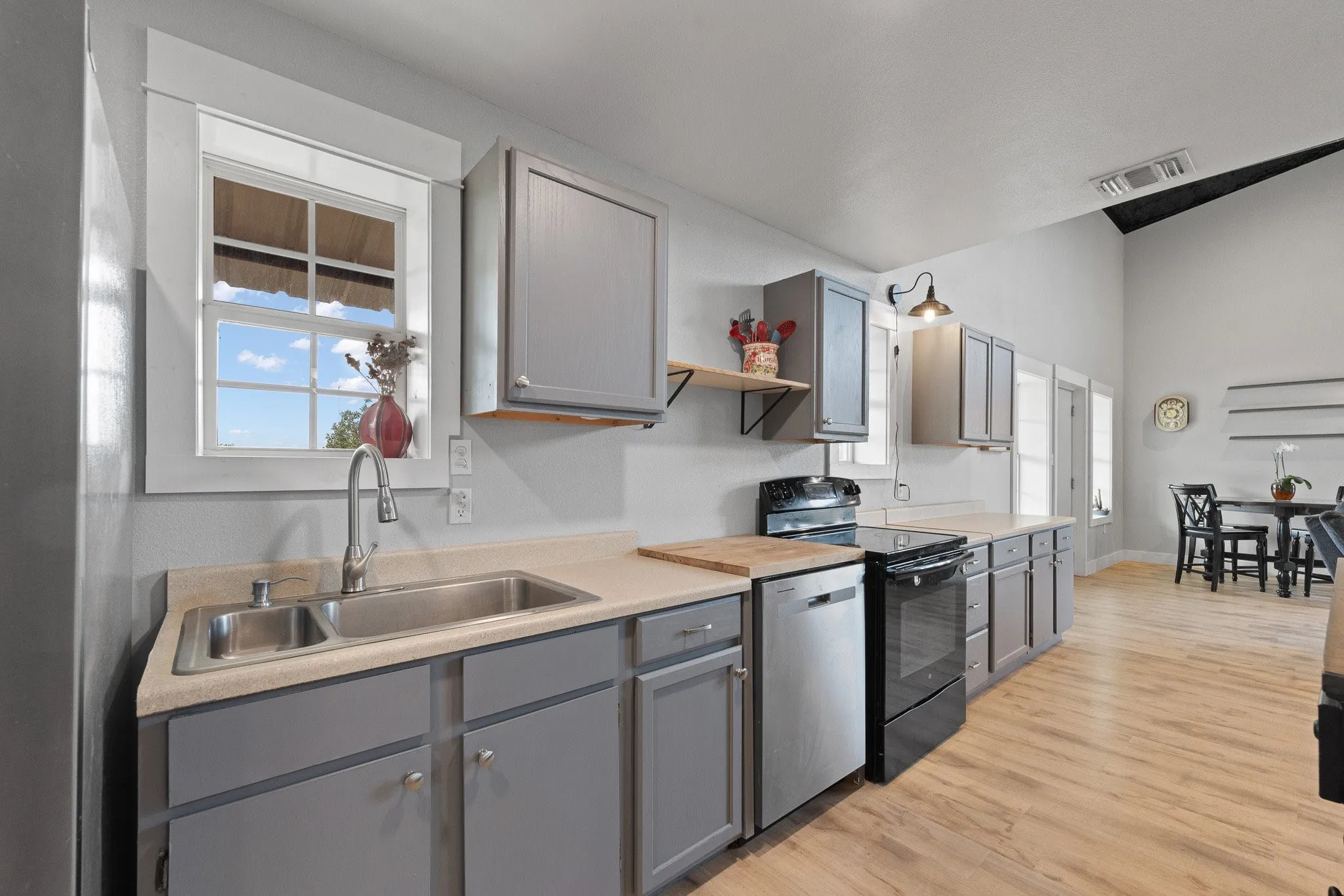 Kitchen featuring gray cabinetry, light countertops, black range with electric cooktop, and open shelves