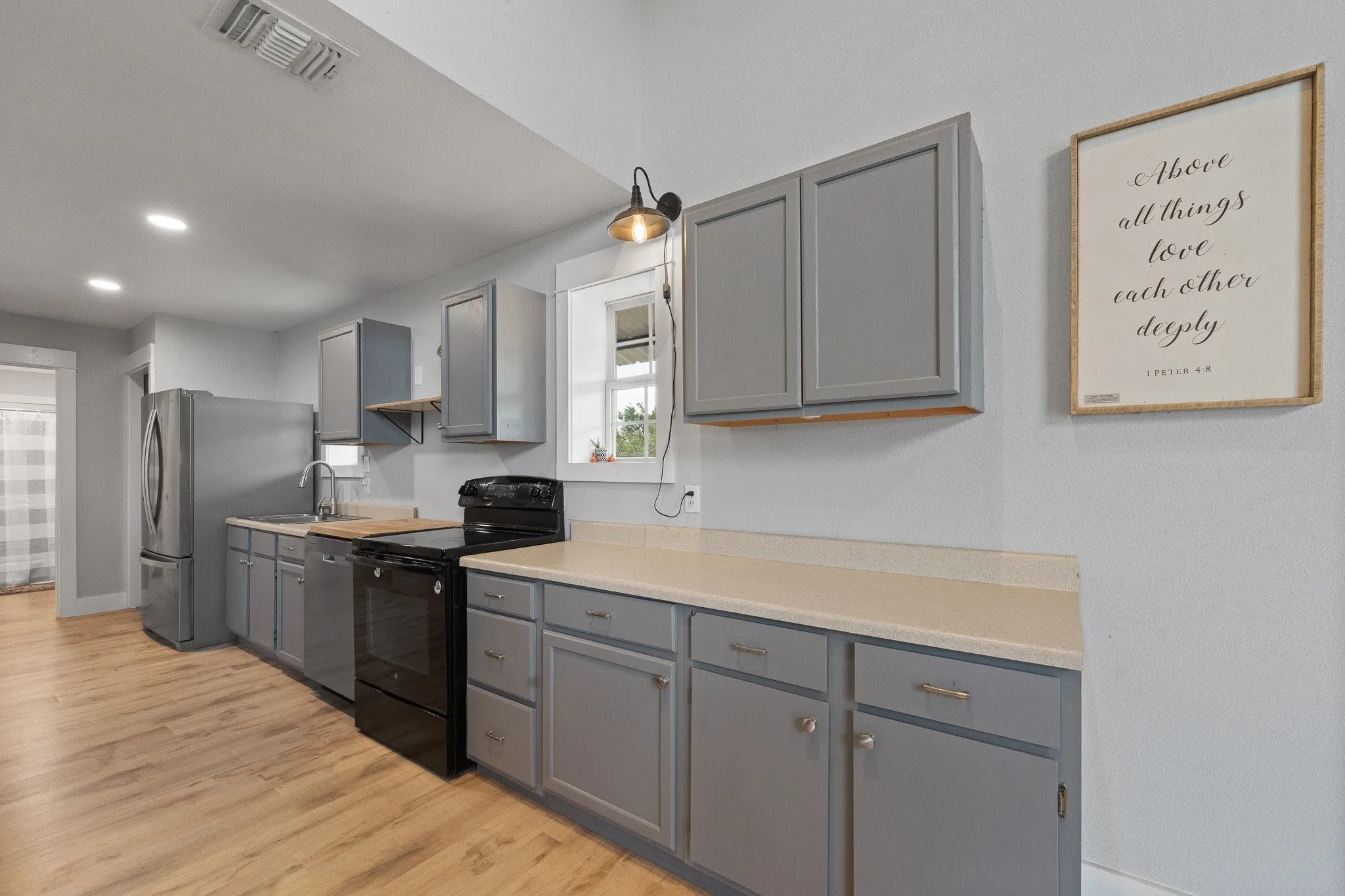 Kitchen with gray cabinets, stainless steel appliances, light countertops, light wood finished floors, and recessed lighting