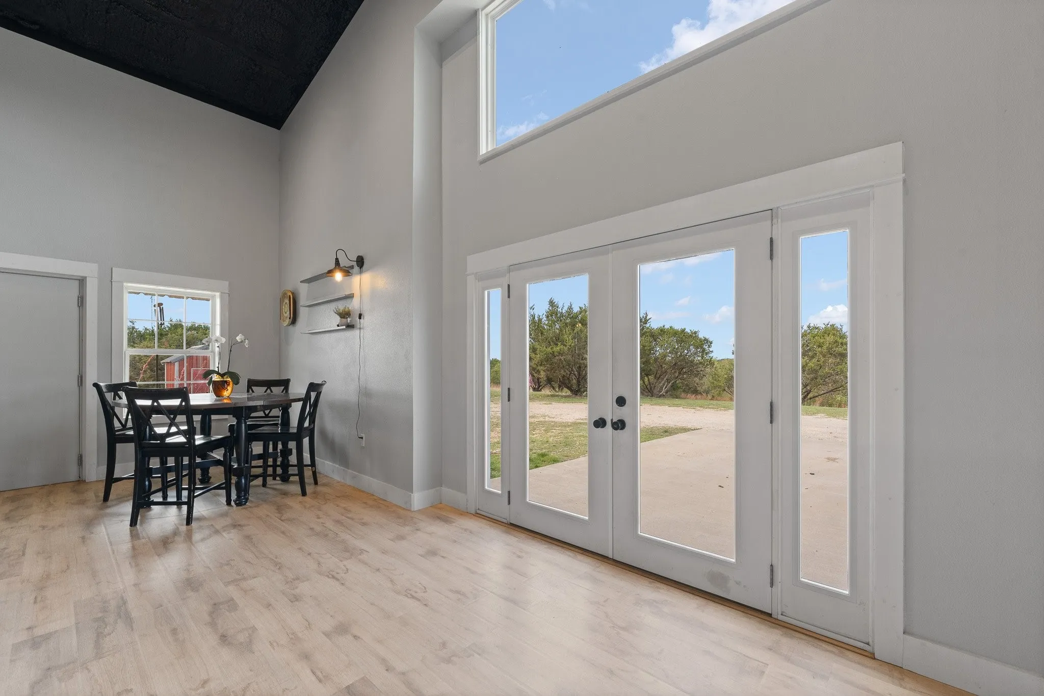 Dining space with french doors, light wood-style floors, and a high ceiling