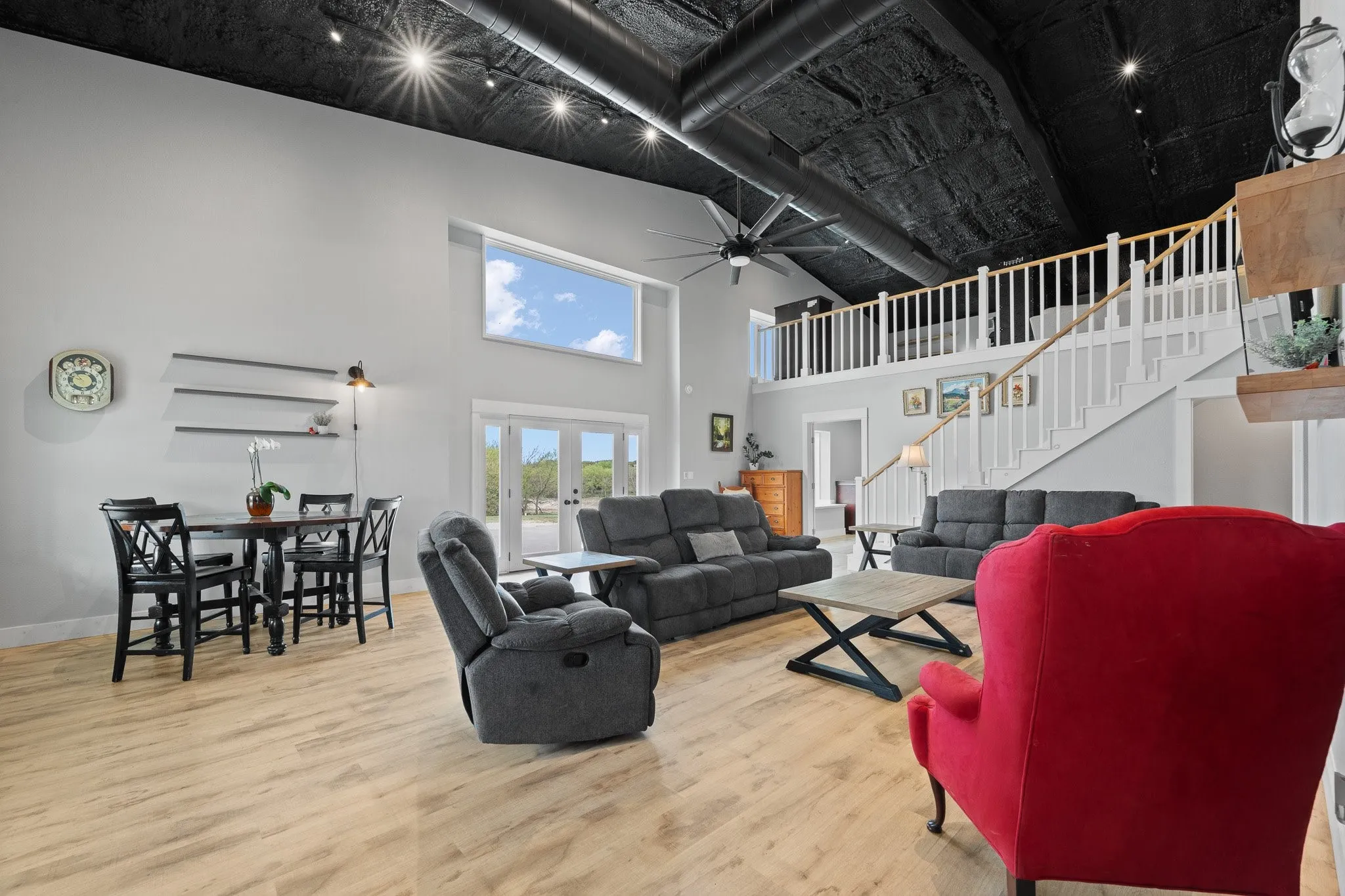 Living room with ceiling fan, light wood-type flooring, a high ceiling, and french doors