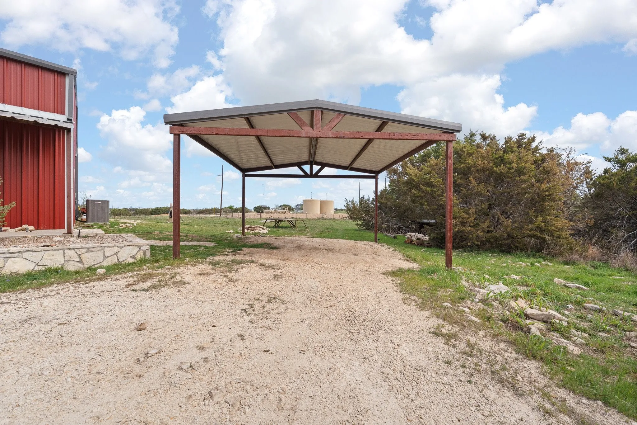 View of parking with dirt driveway and a detached carport