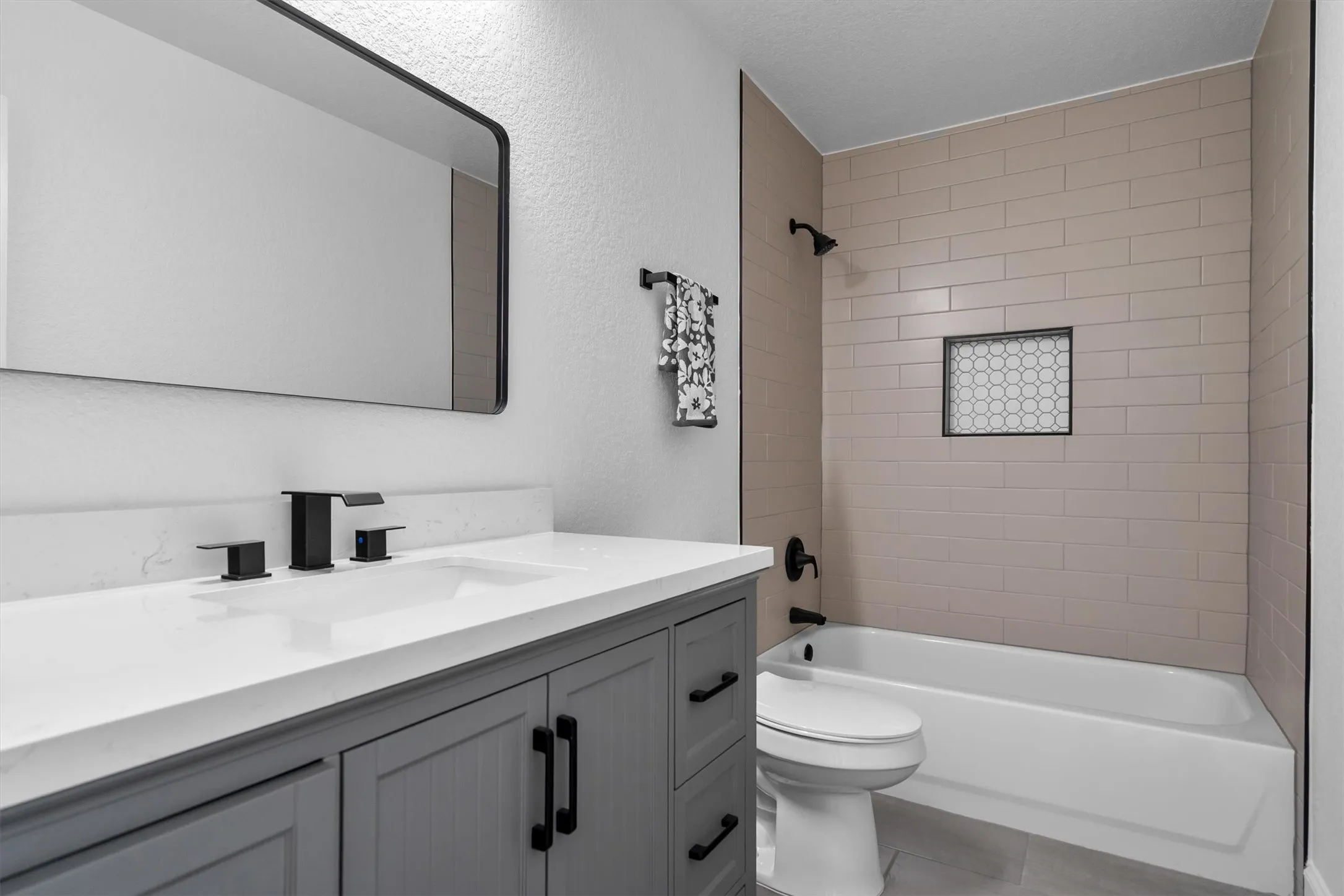 Fully updated secondary bathroom with all new vanity, mirror, lighting, tile floor, toilet, and tilework