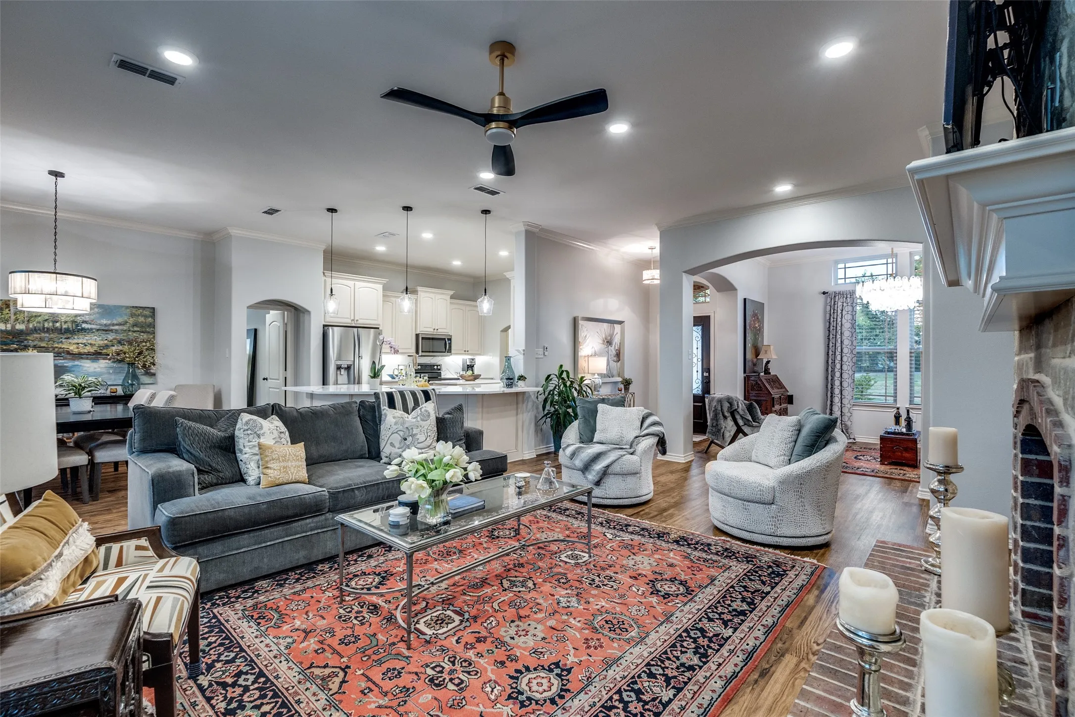 Living area featuring arched walkways, wood finished floors, ceiling fan, hanging lights, and a fireplace