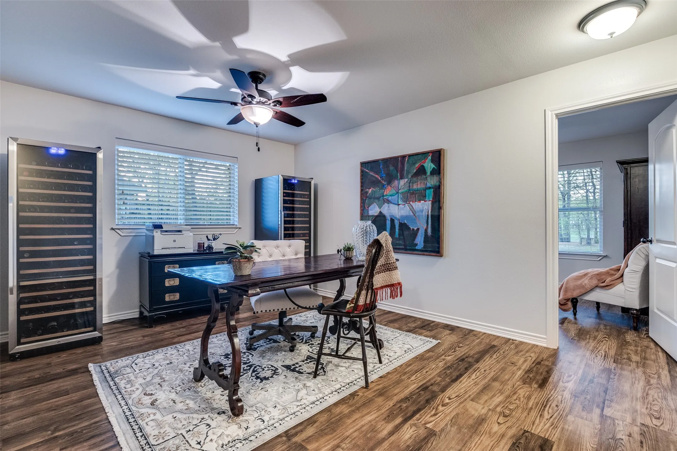 Home office with wine cooler, ceiling fan, and dark wood-type flooring