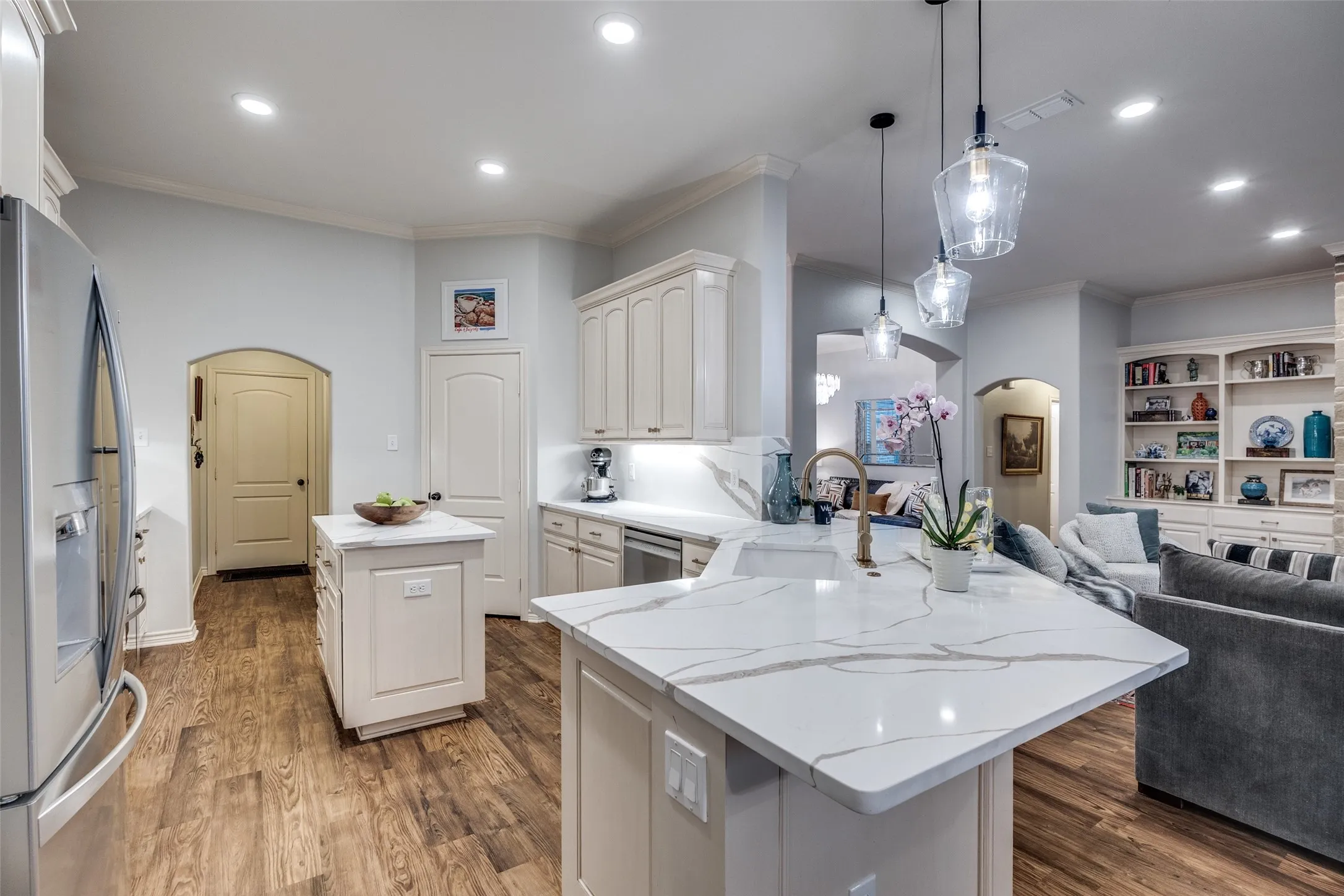 Kitchen featuring arched walkways, a center island, open floor plan, crown molding, and a peninsula