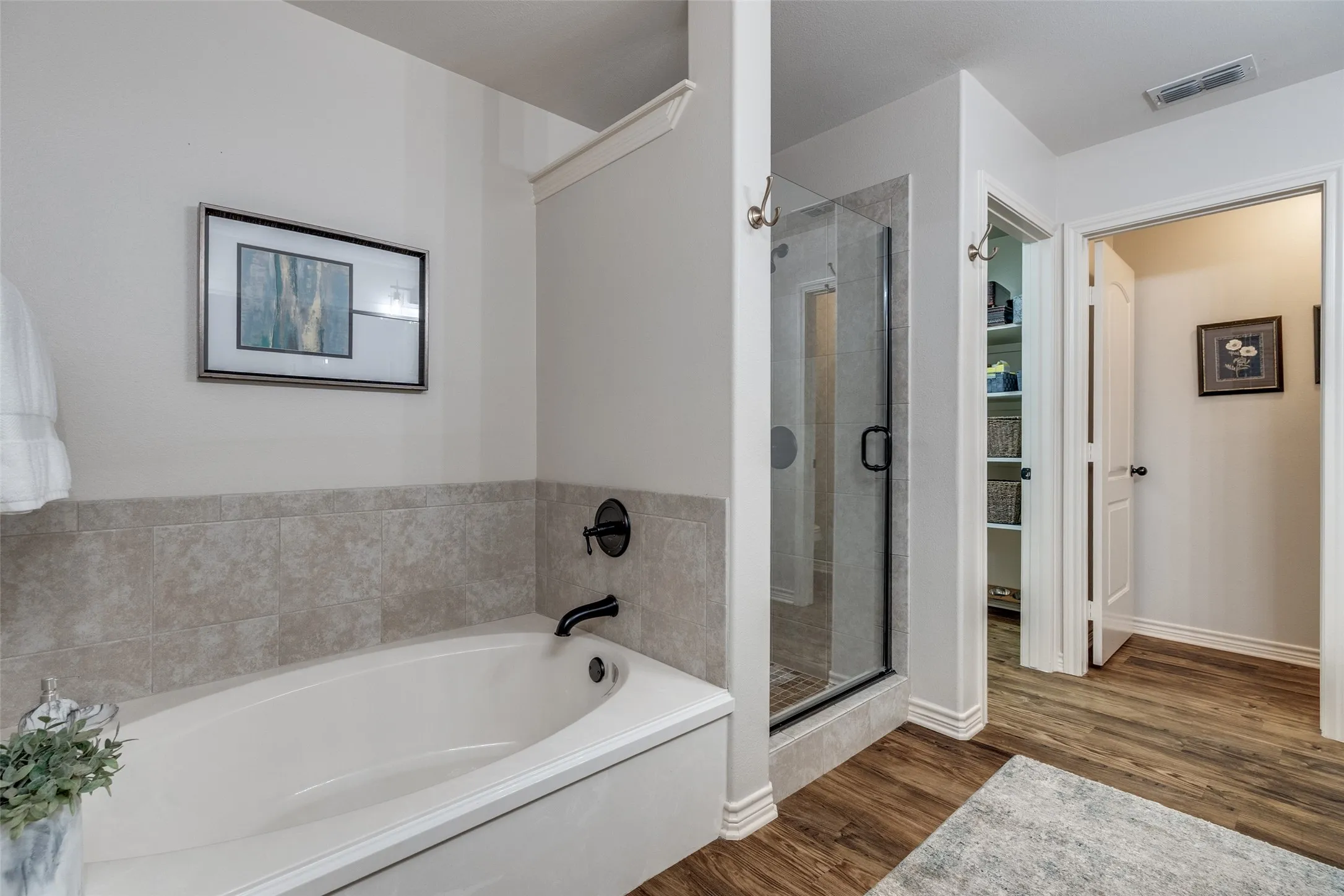Full bath with a shower stall, a bath, and dark wood-style floors