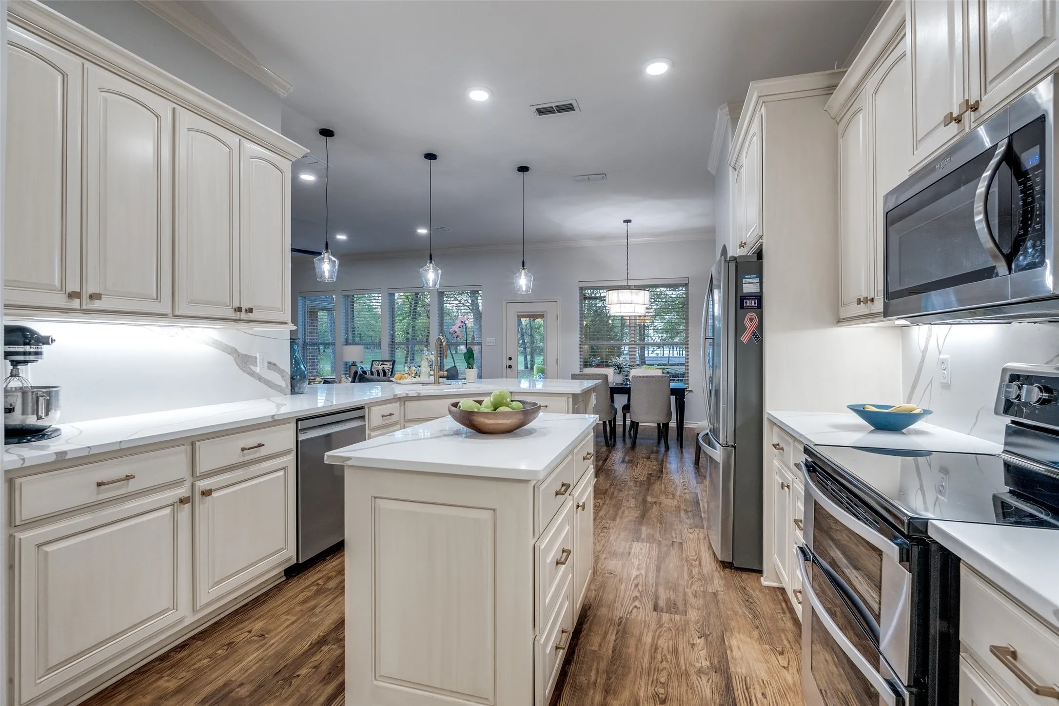 Kitchen featuring stainless steel appliances, a peninsula, pendant lighting, crown molding, and a kitchen island