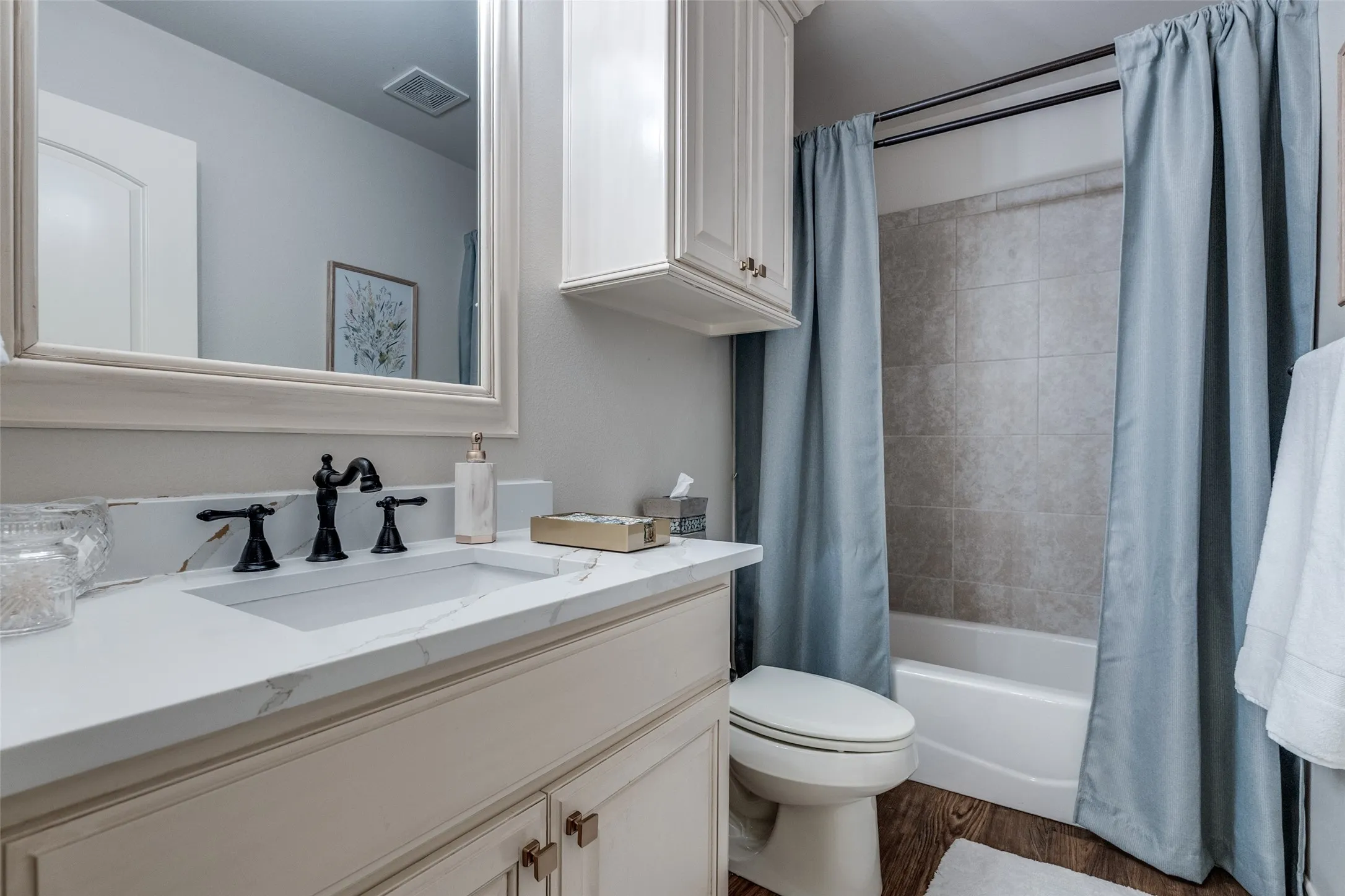 Bathroom featuring vanity, shower / tub combo, and dark wood-style flooring