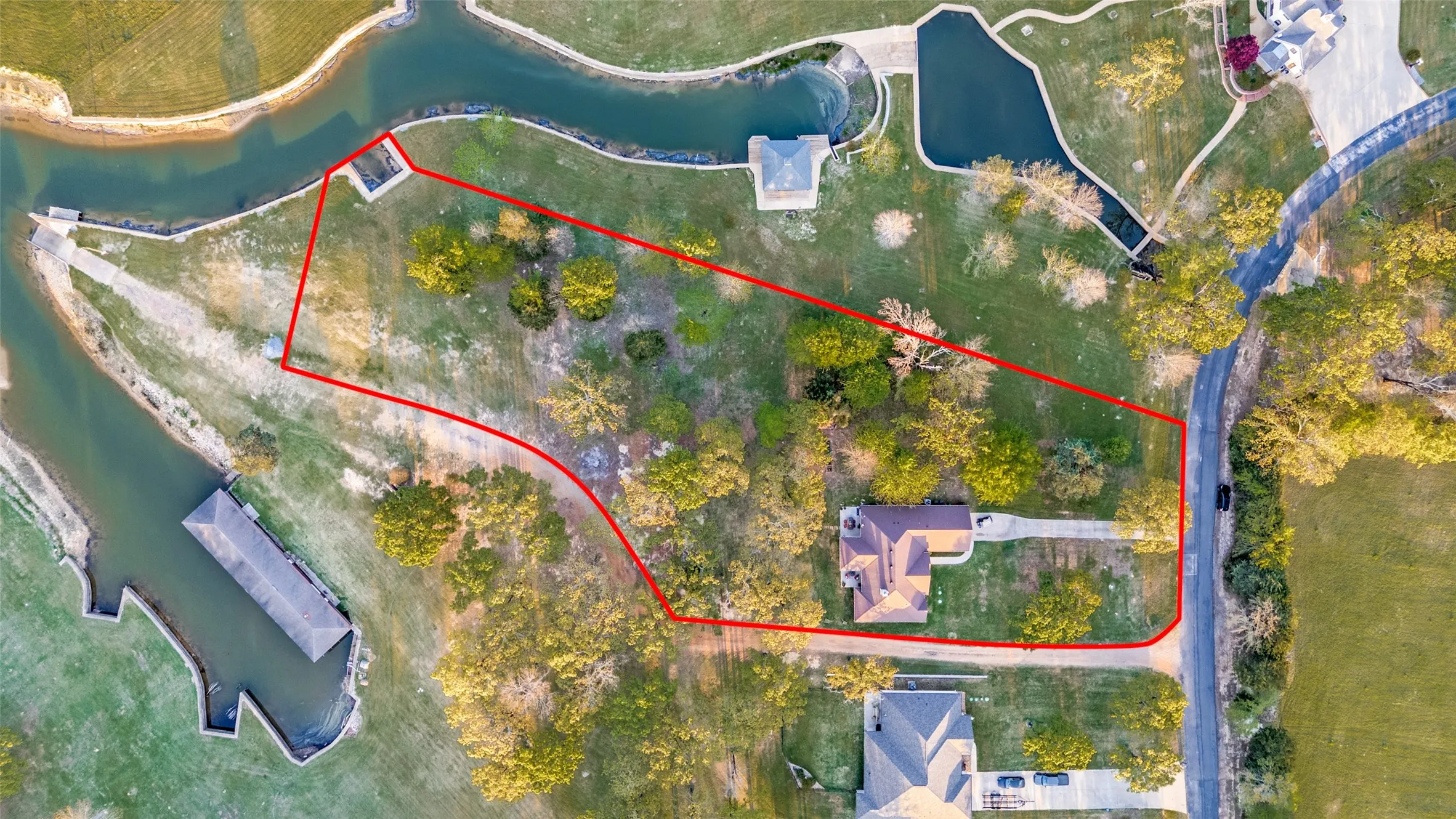 Aerial view of property and surrounding area featuring a nearby body of water and property parcel outlined