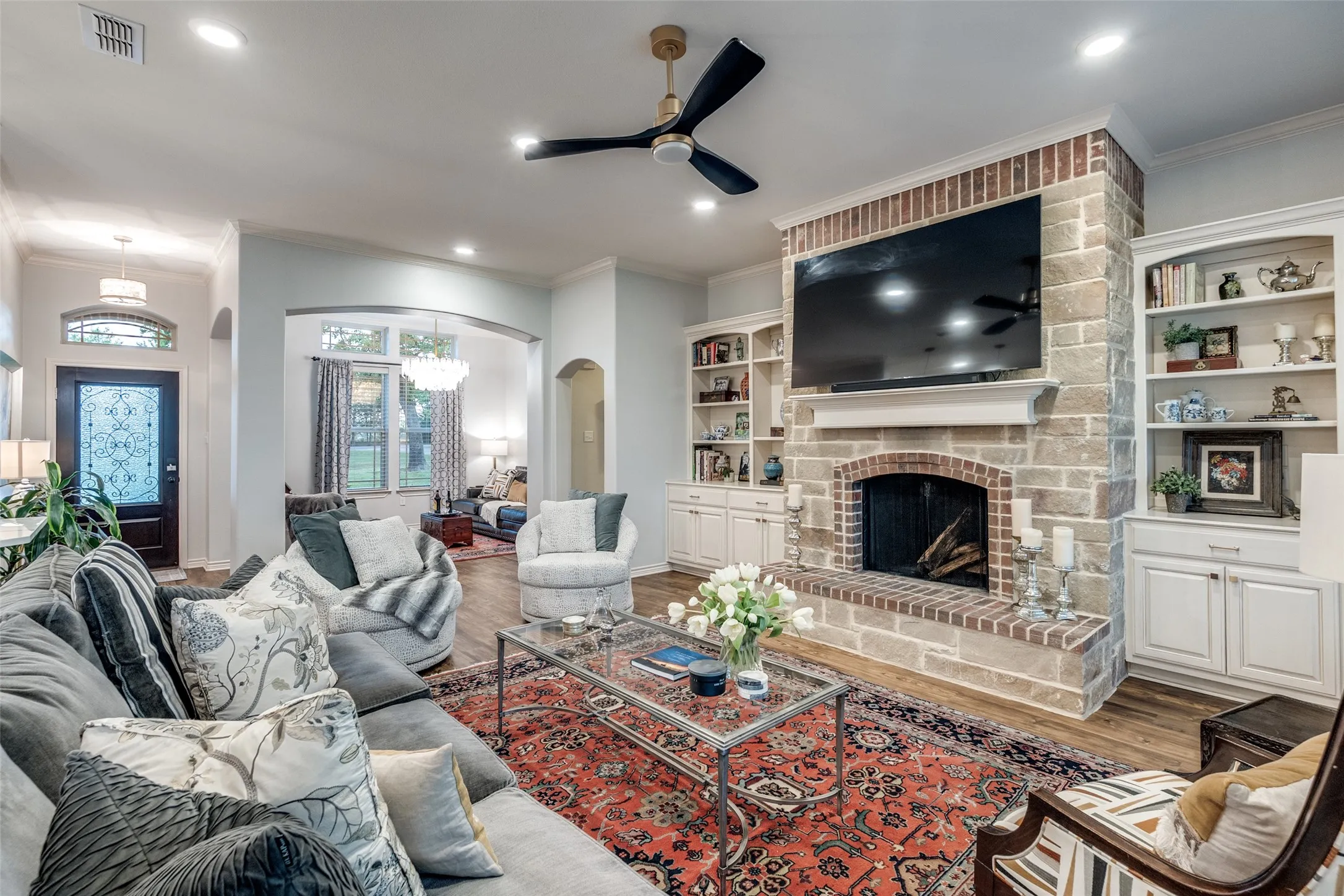Living area featuring crown molding, a fireplace, ceiling fan, arched walkways, and wood finished floors