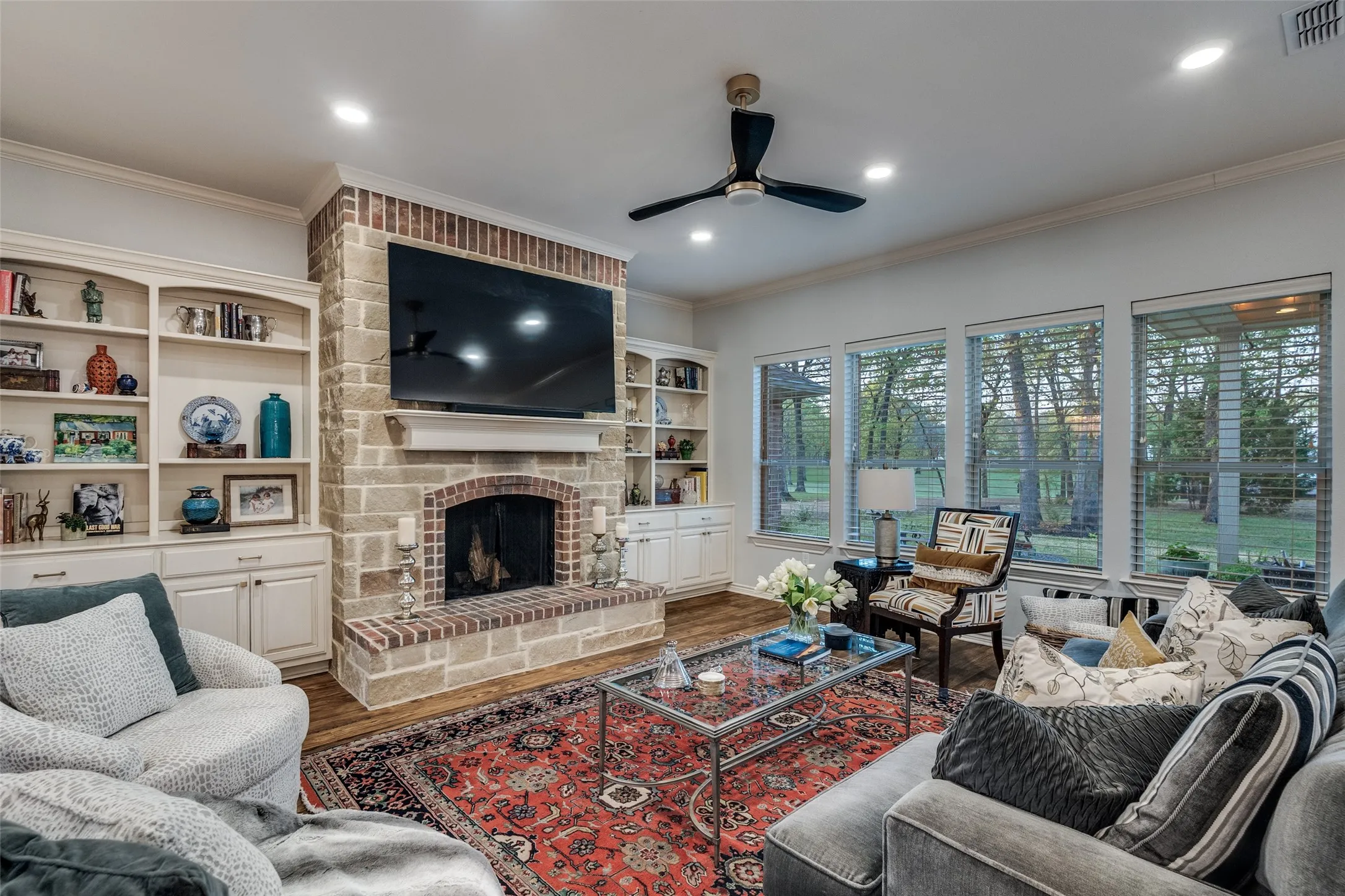 Living room featuring a ceiling fan, a fireplace, wood finished floors, ornamental molding, and recessed lighting