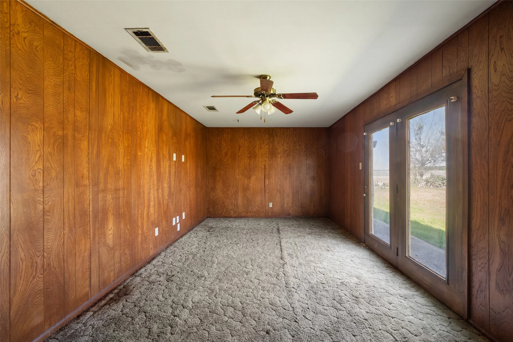 Carpeted unfurnished living room featuring paneling