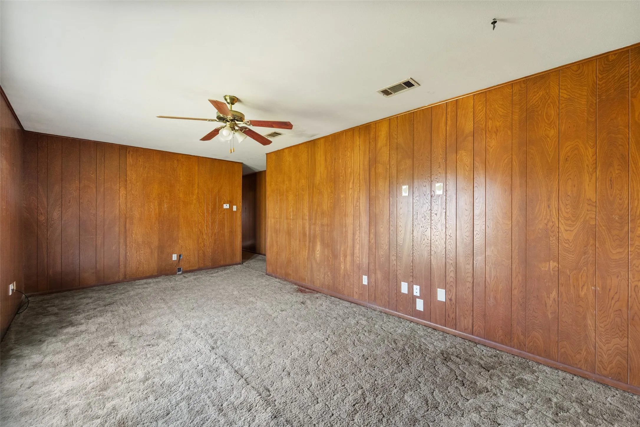 Carpeted unfurnished living room featuring paneling