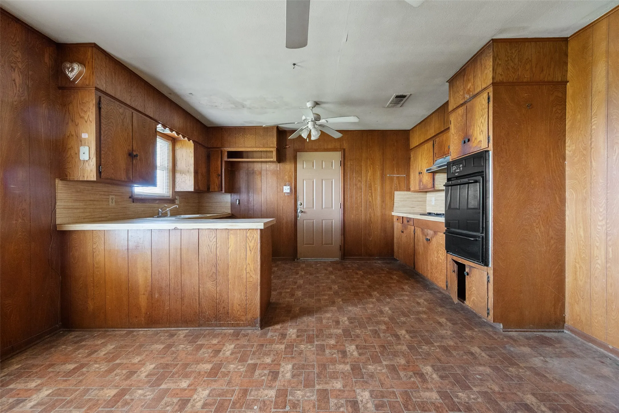 Kitchen featuring wood cabinets, a peninsula, light countertops, and brick patterned flooring