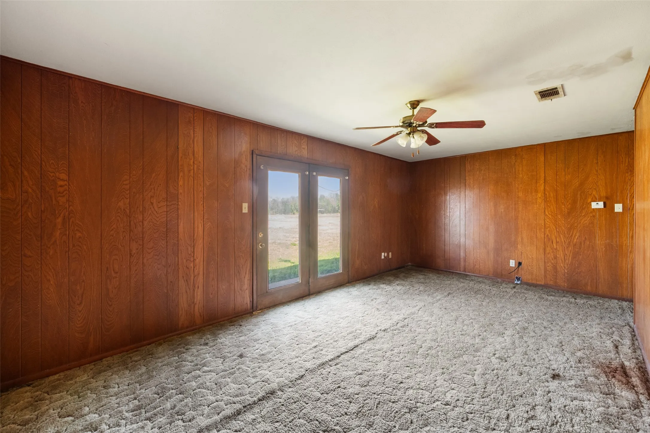 Carpeted unfurnished living room featuring paneling