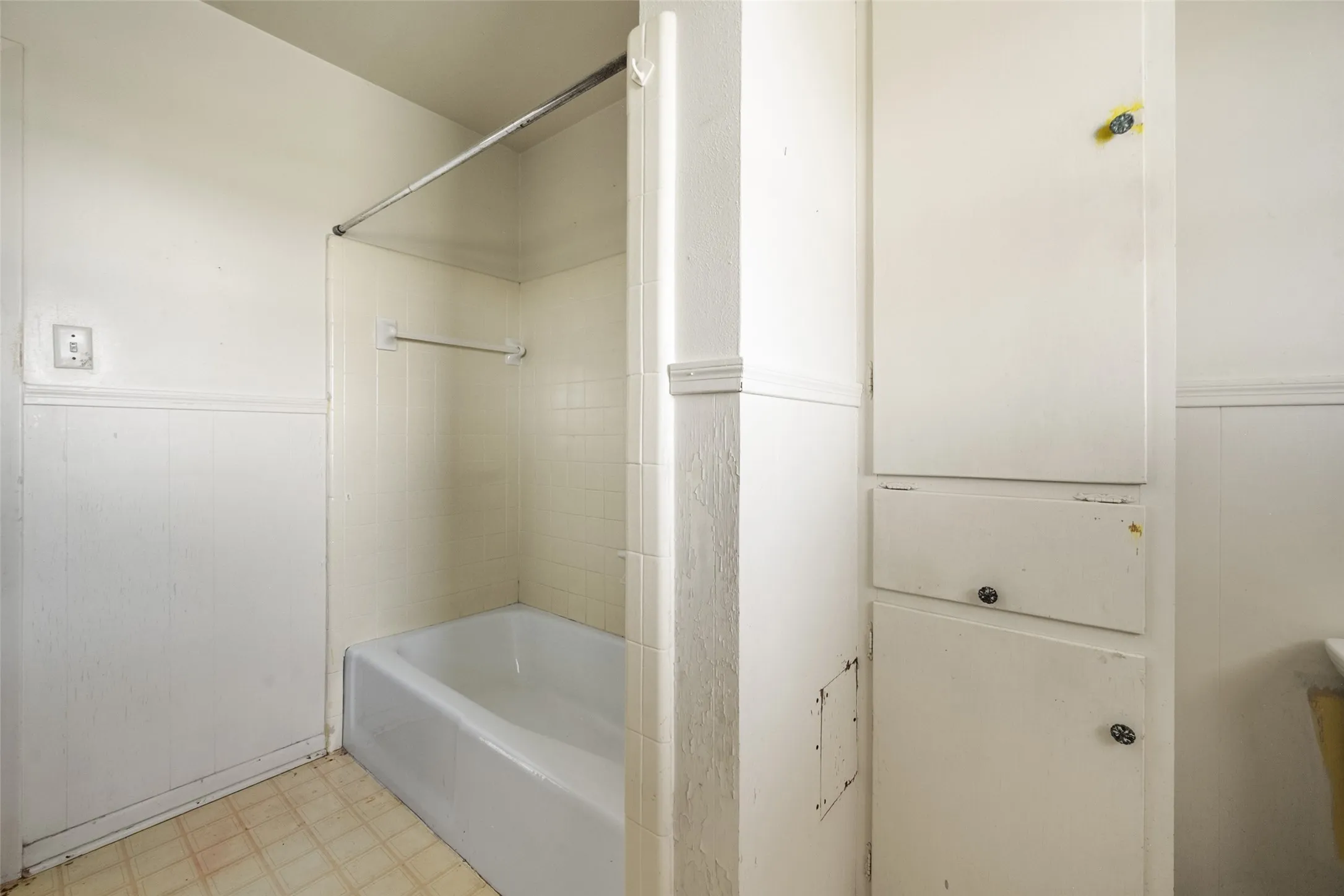 Bathroom with light flooring, a wainscoted wall, and  shower combination
