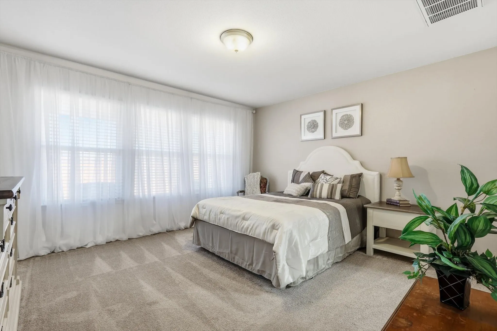 Primary Bedroom with light carpet and a wall of windows