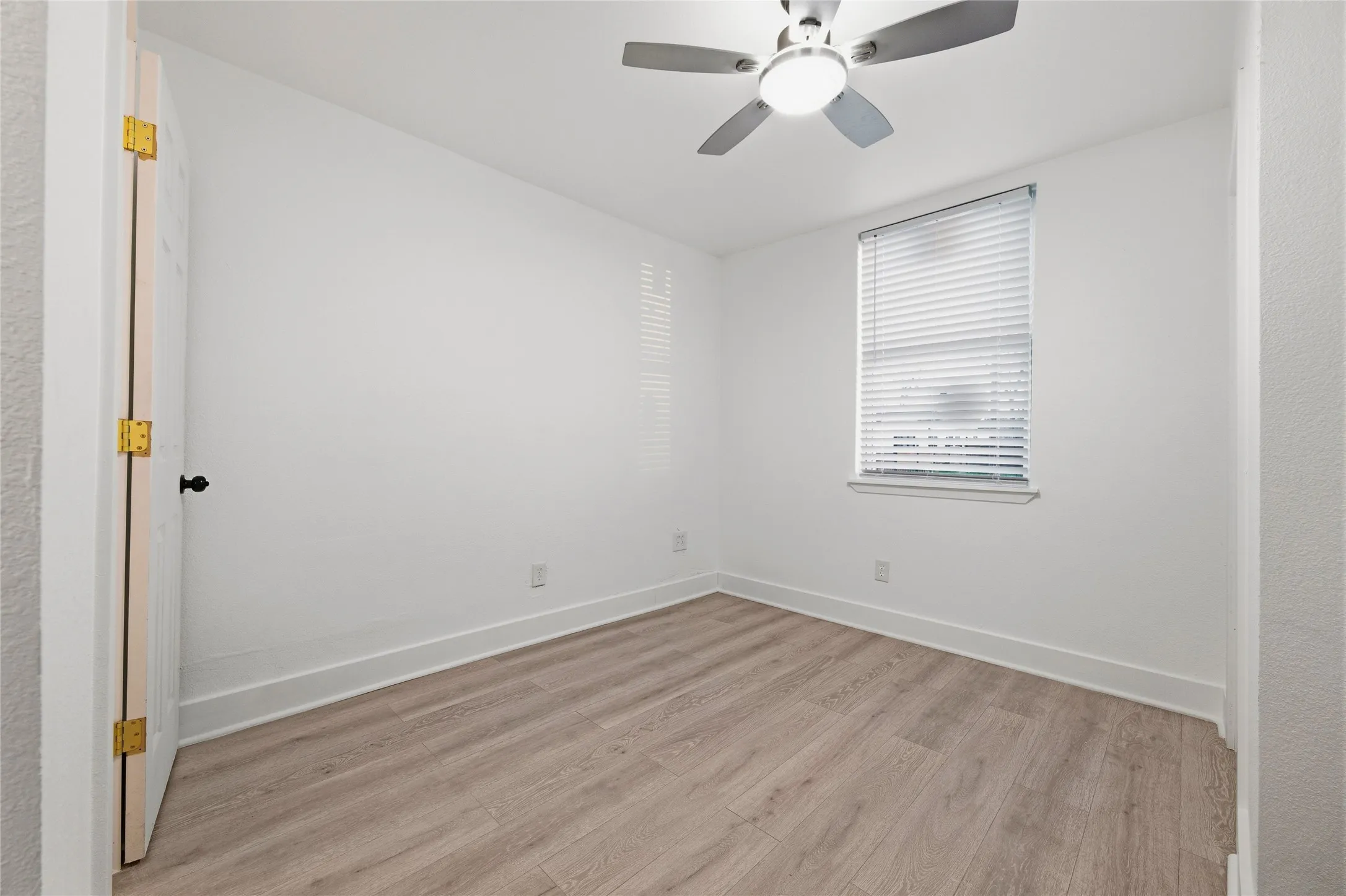 Empty room with light wood-type flooring and a ceiling fan