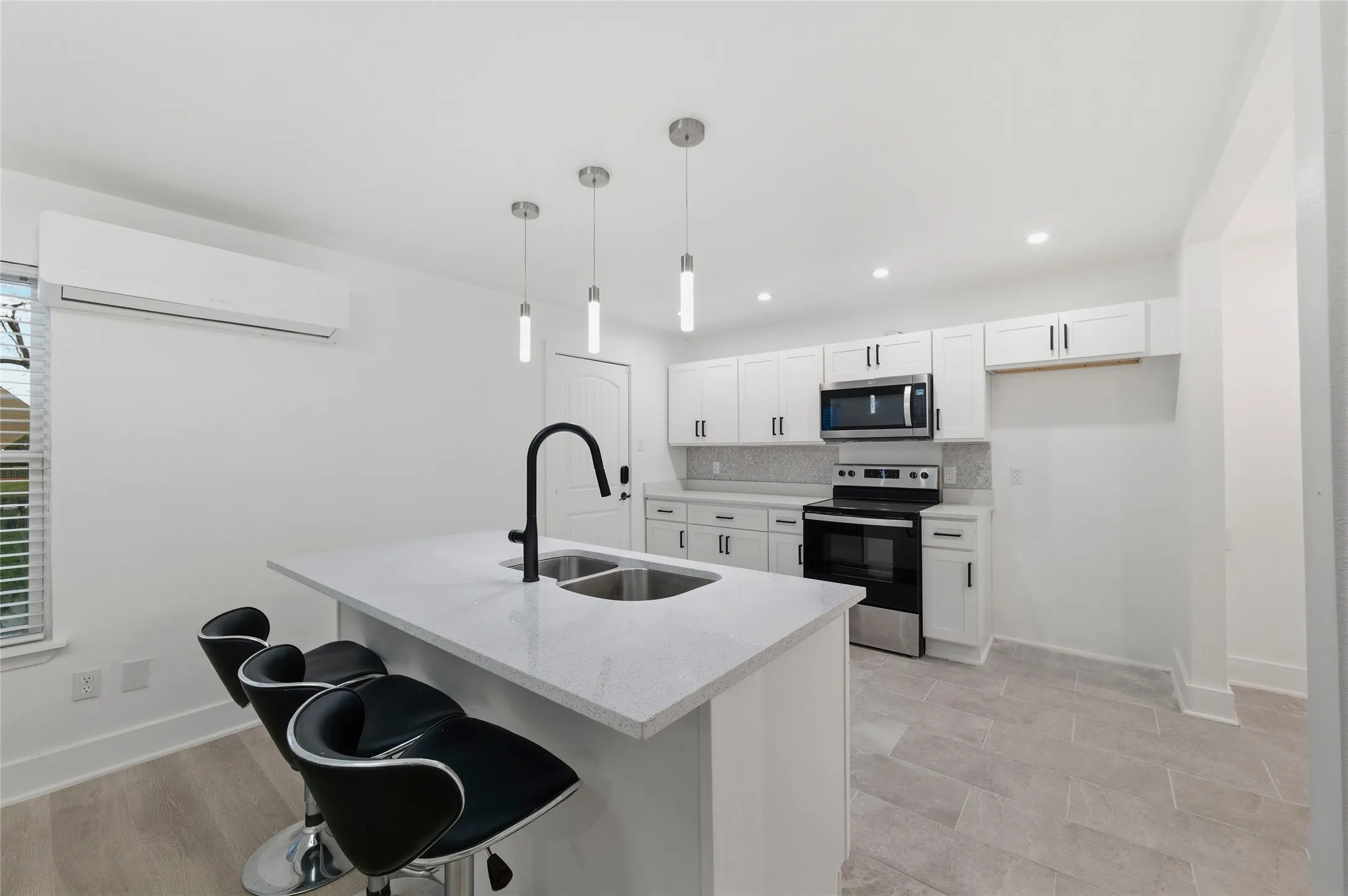 Kitchen with stainless steel appliances, white cabinets, a kitchen bar, tasteful backsplash, and light stone countertops