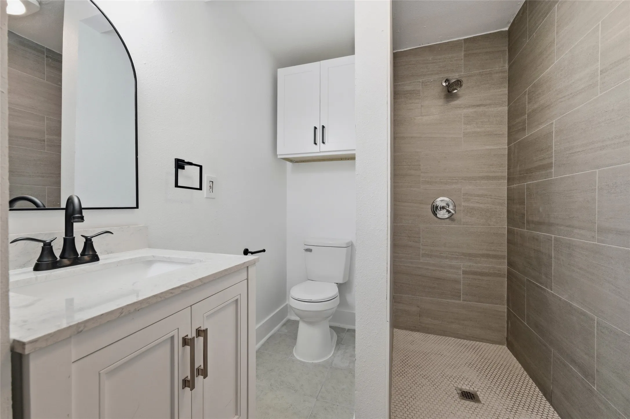 Bathroom with vanity, a tile shower, and light tile patterned flooring
