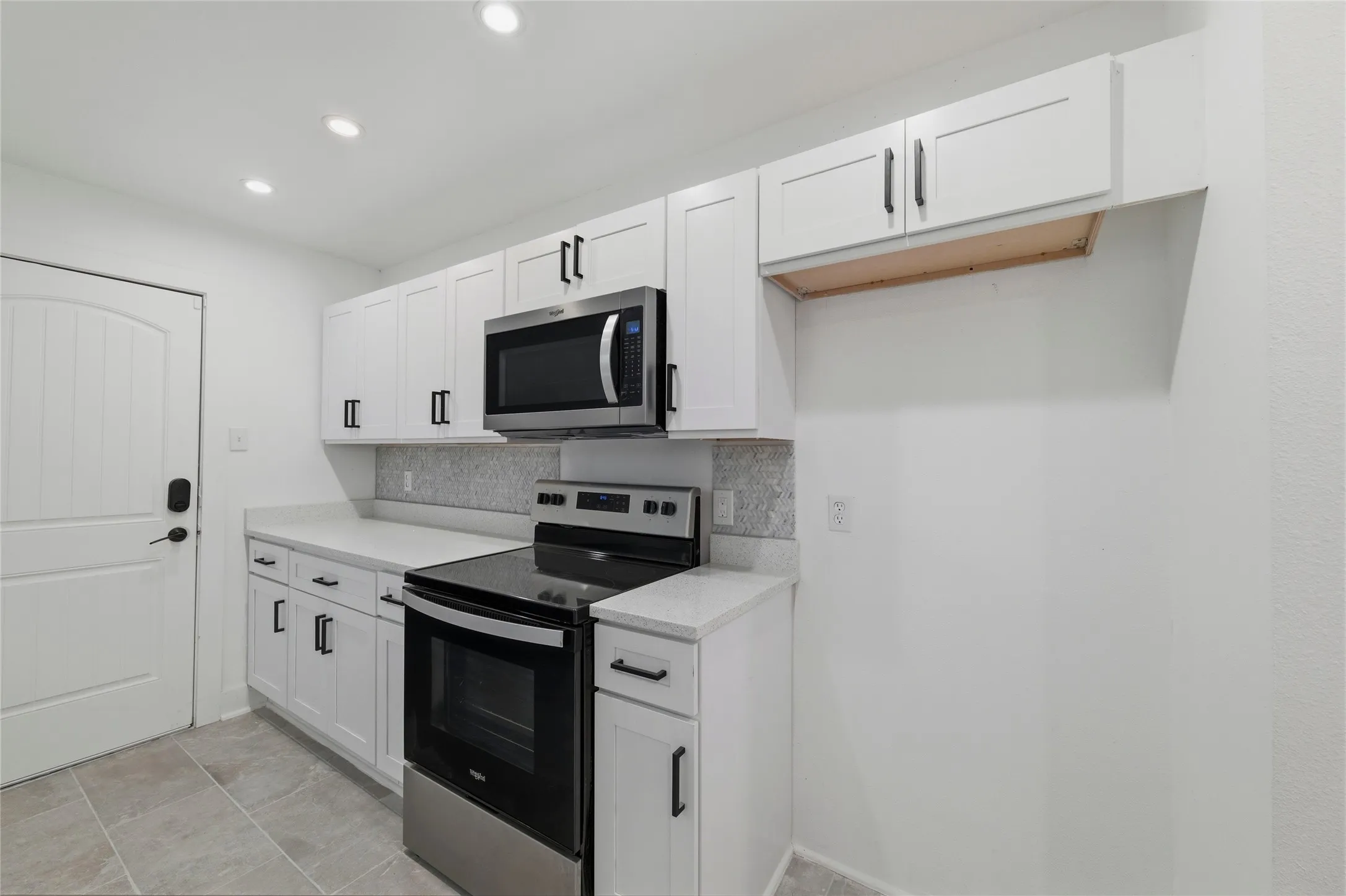 Kitchen featuring white cabinetry, stainless steel appliances, decorative backsplash, and recessed lighting
