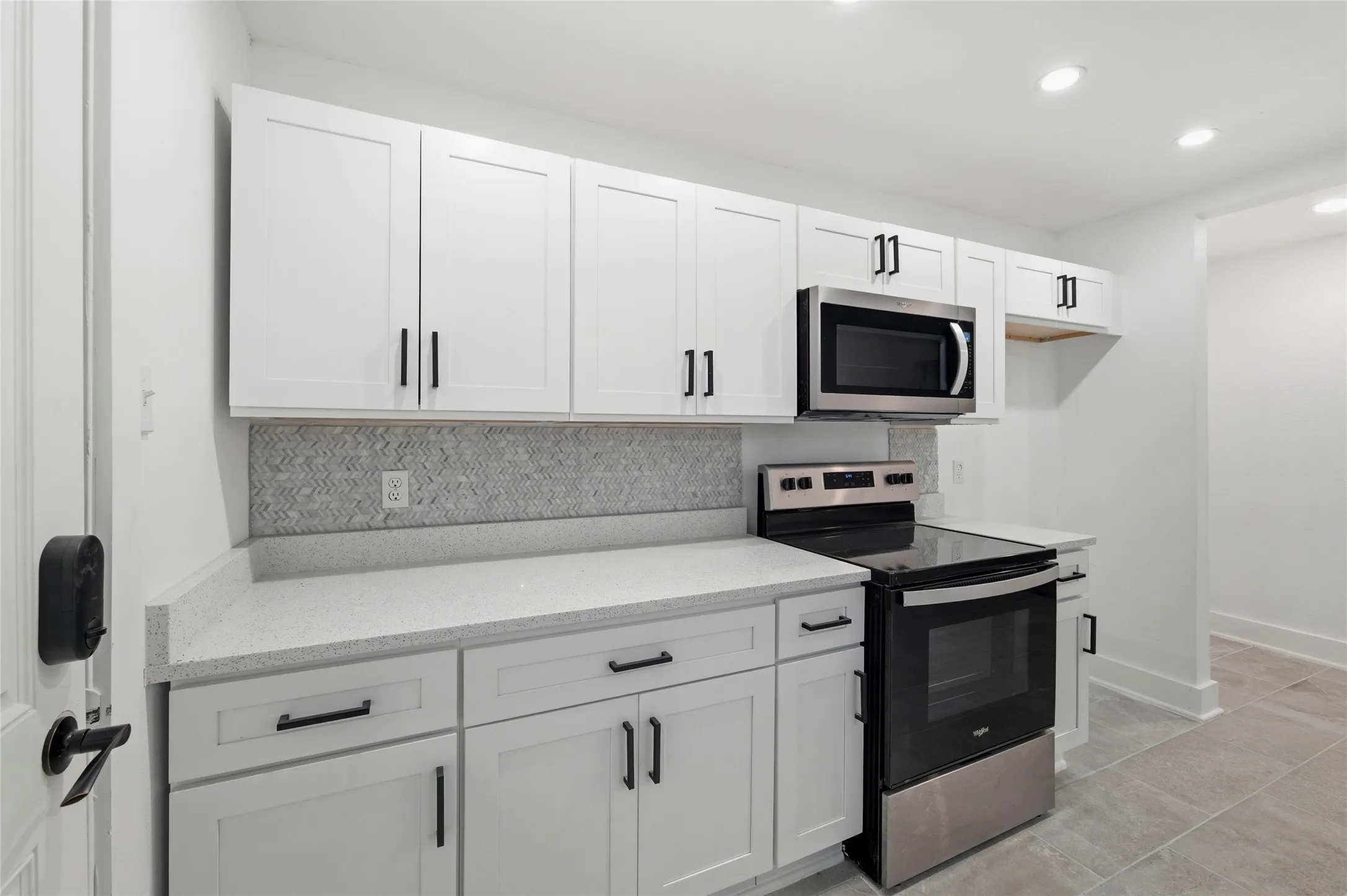 Kitchen featuring stainless steel appliances, white cabinets, recessed lighting, light stone counters, and light tile patterned flooring