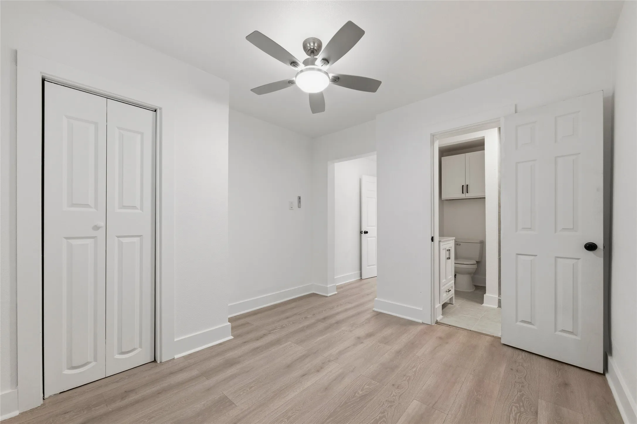 Unfurnished bedroom featuring light wood-style floors, a closet, ceiling fan, and connected bathroom