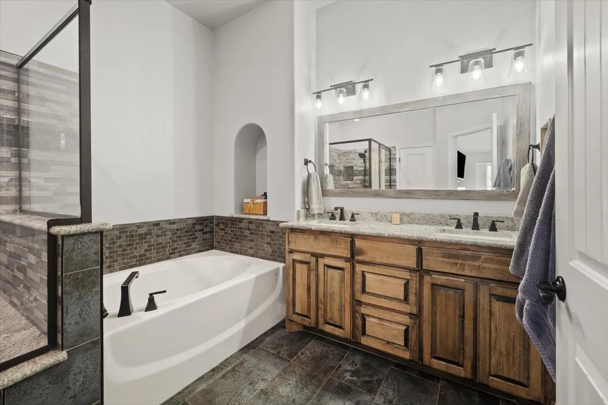 Full bathroom featuring double vanity, a garden tub, and a shower stall