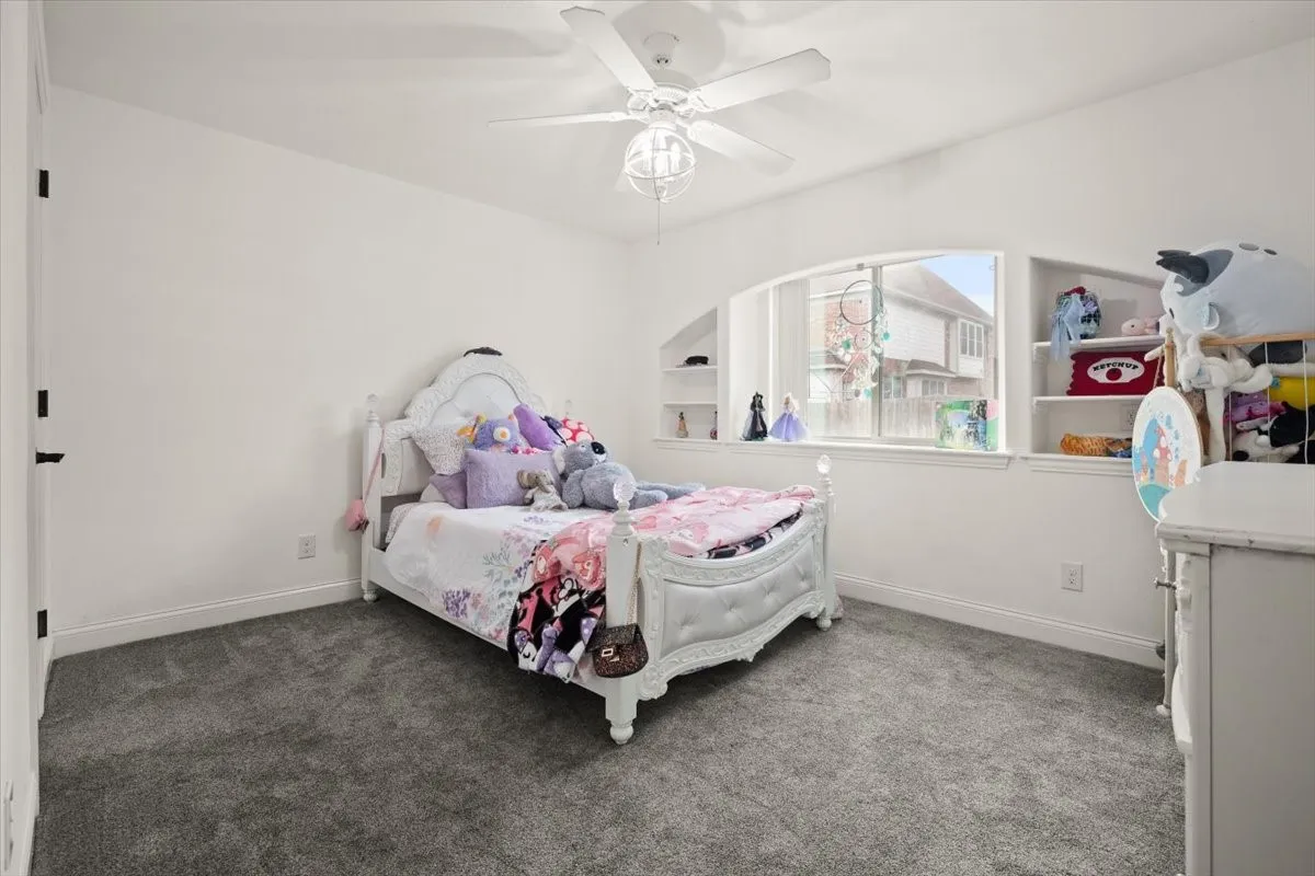 Carpeted bedroom featuring a ceiling fan and baseboards