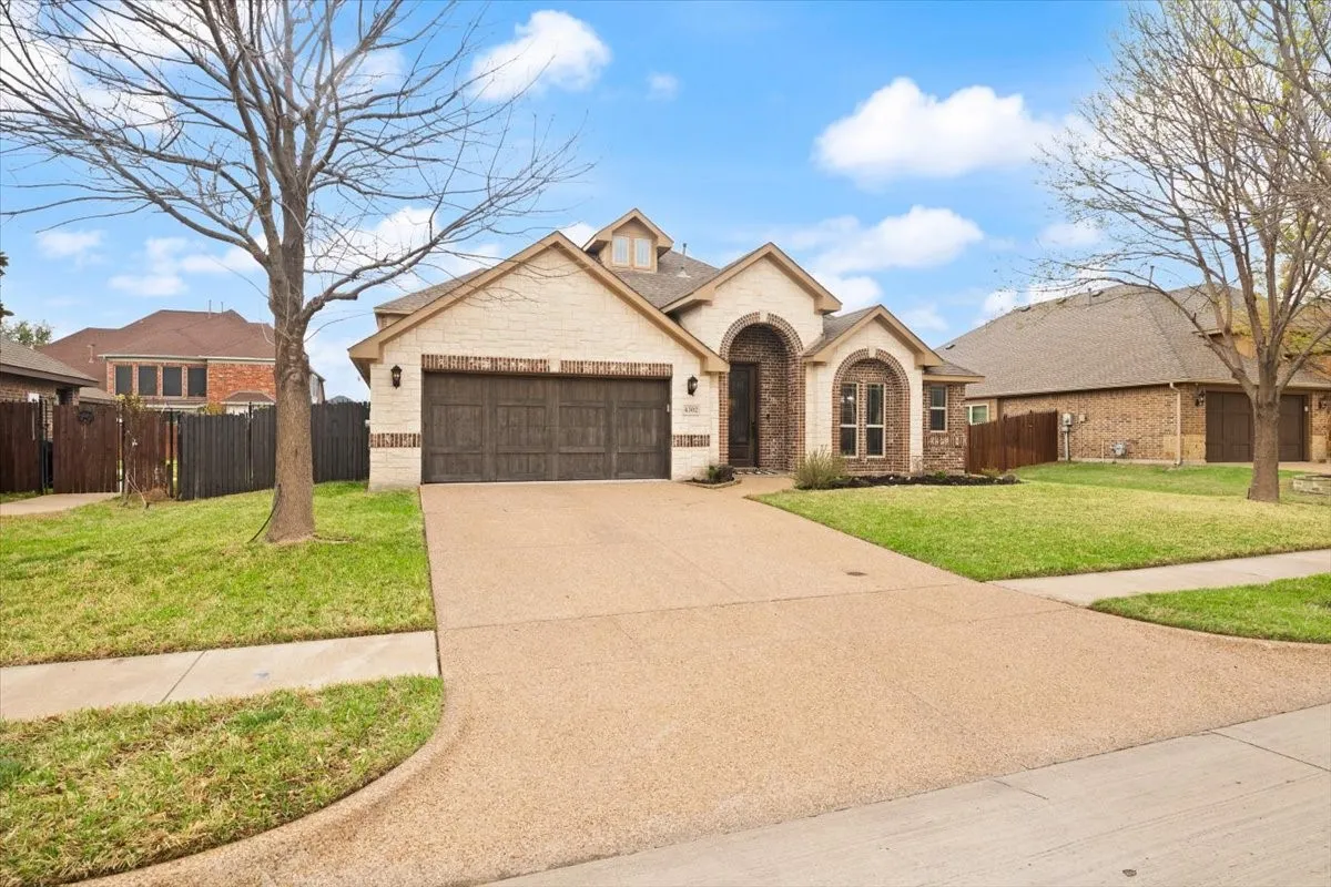 View of front of property with brick siding, driveway, and a garage