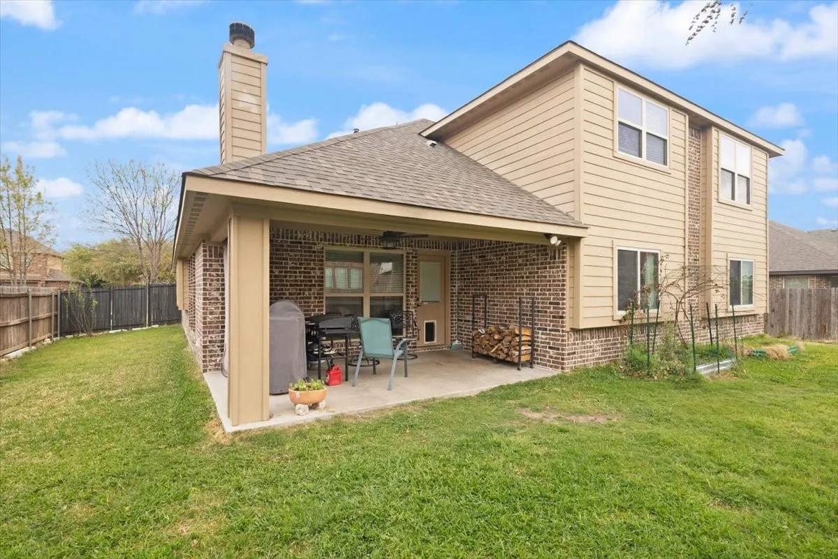 Back of house with a fenced backyard, brick siding, a patio area, roof with shingles, and a chimney