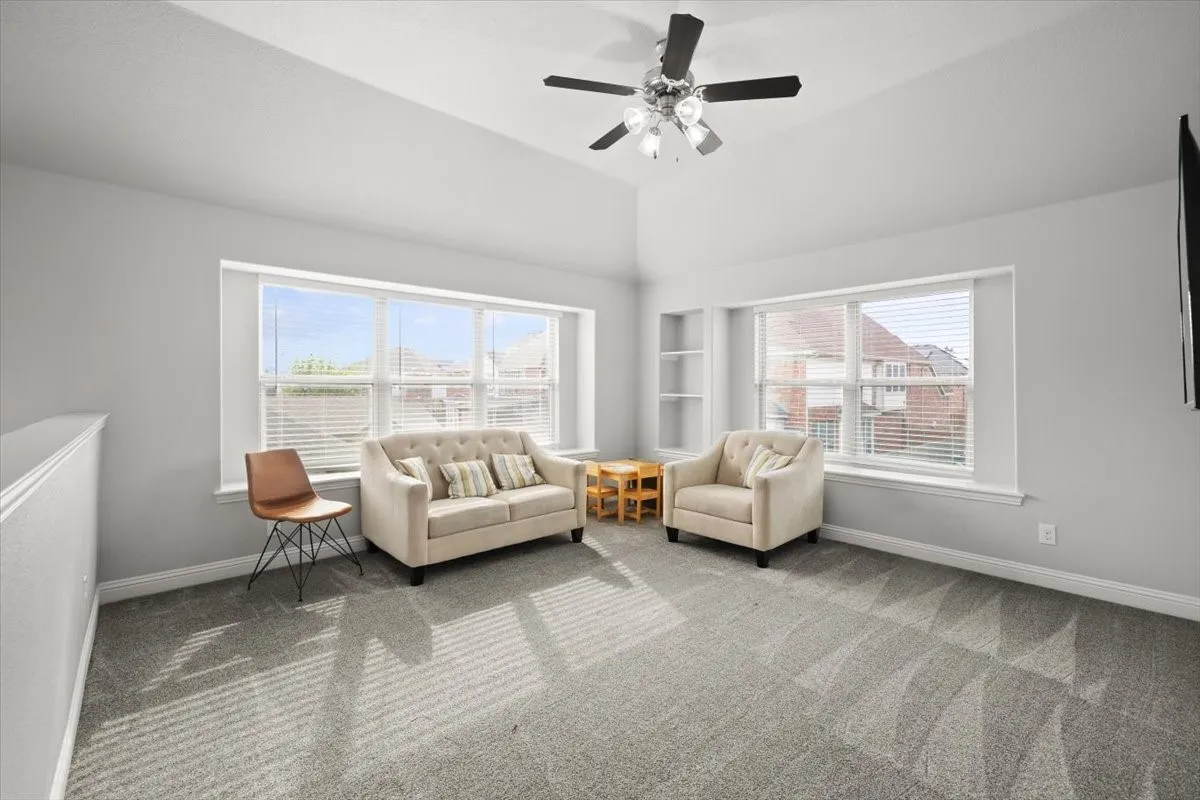 Living area featuring carpet flooring, plenty of natural light, and ceiling fan
