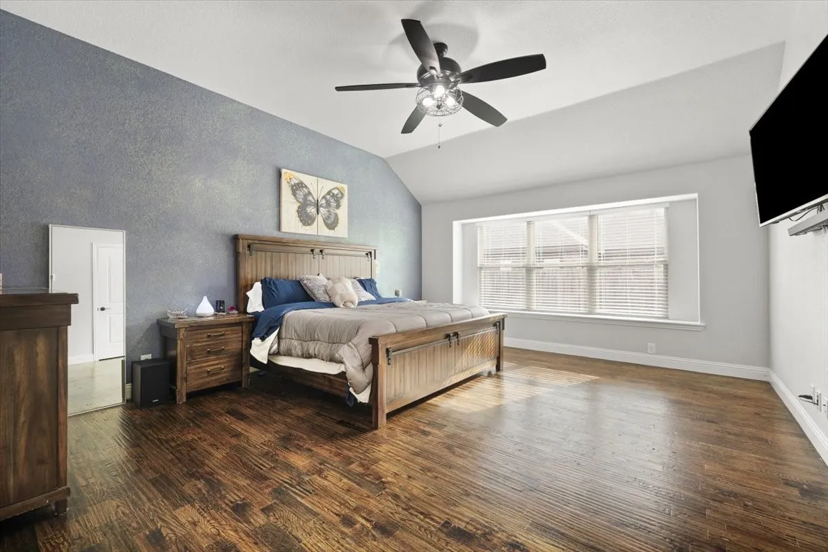 Bedroom featuring dark wood-style flooring, lofted ceiling, and a ceiling fan