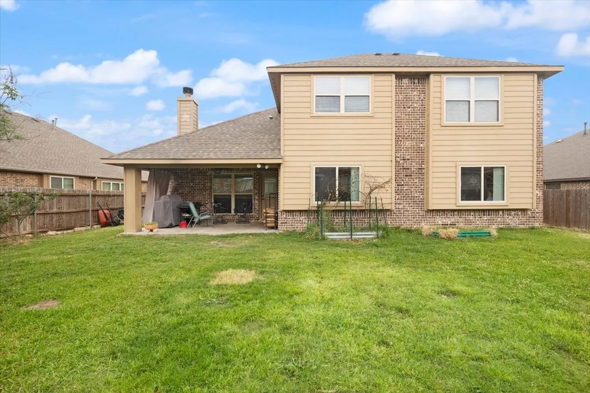 Back of property with a fenced backyard, a patio, brick siding, roof with shingles, and a chimney