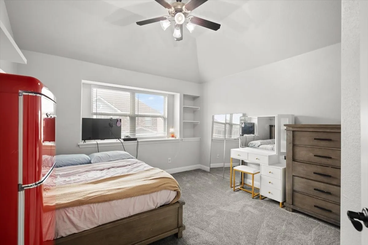 Bedroom with windows, light carpet, ceiling fan, and vaulted ceiling