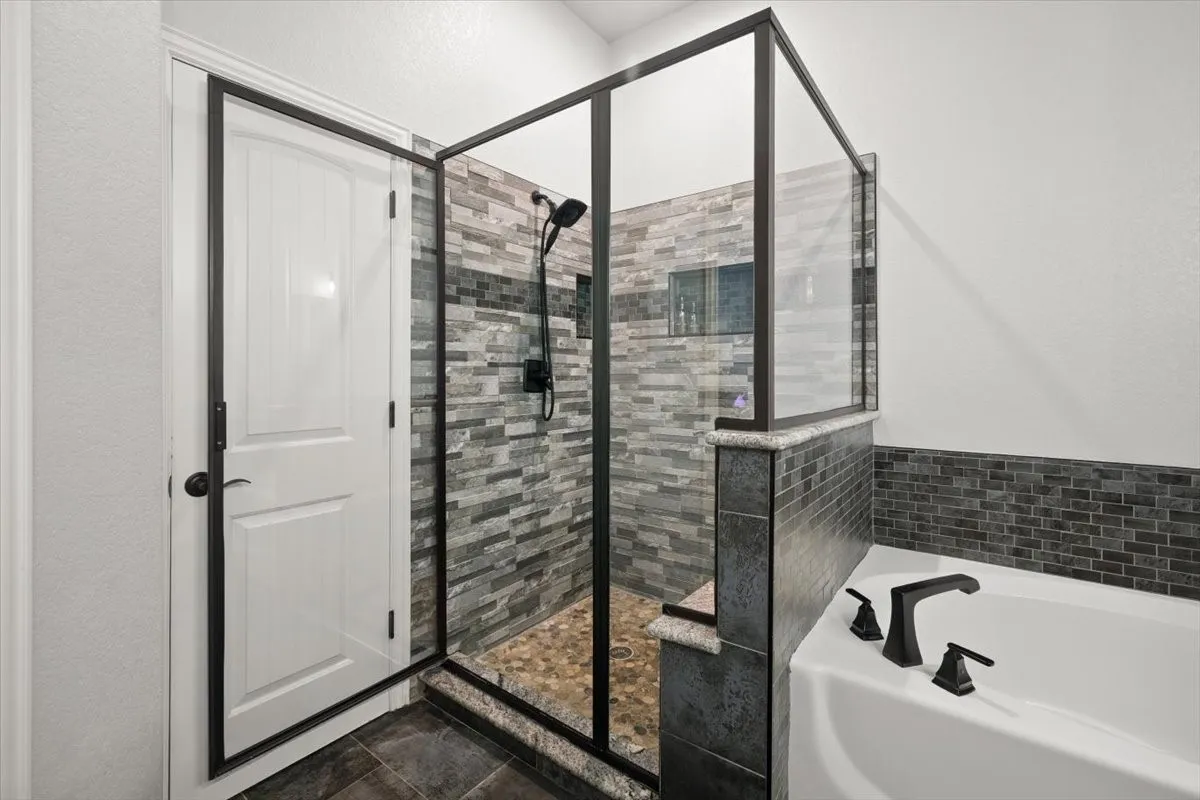 Bathroom featuring a bath, a stall shower, and a textured wall