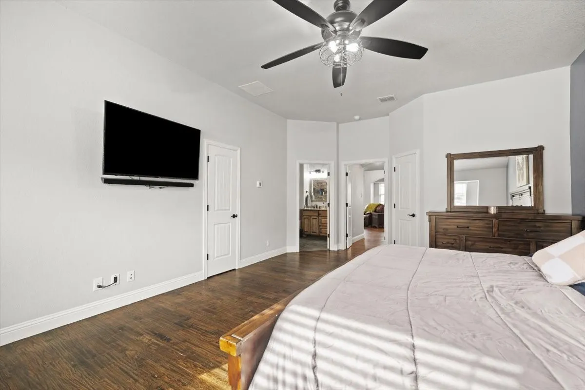 Bedroom with dark wood-style flooring, ensuite bathroom, and ceiling fan