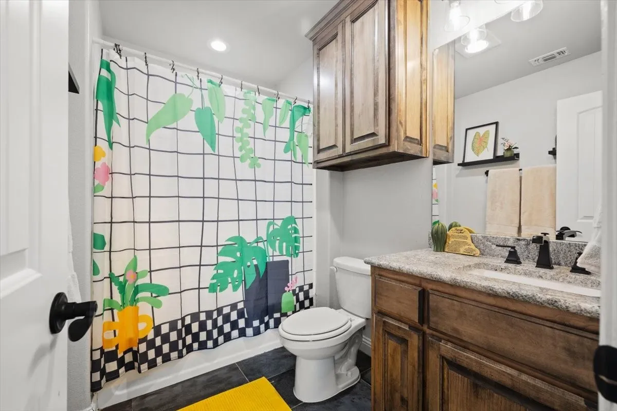 Full bath with vanity, dark tile patterned floors, and recessed lighting