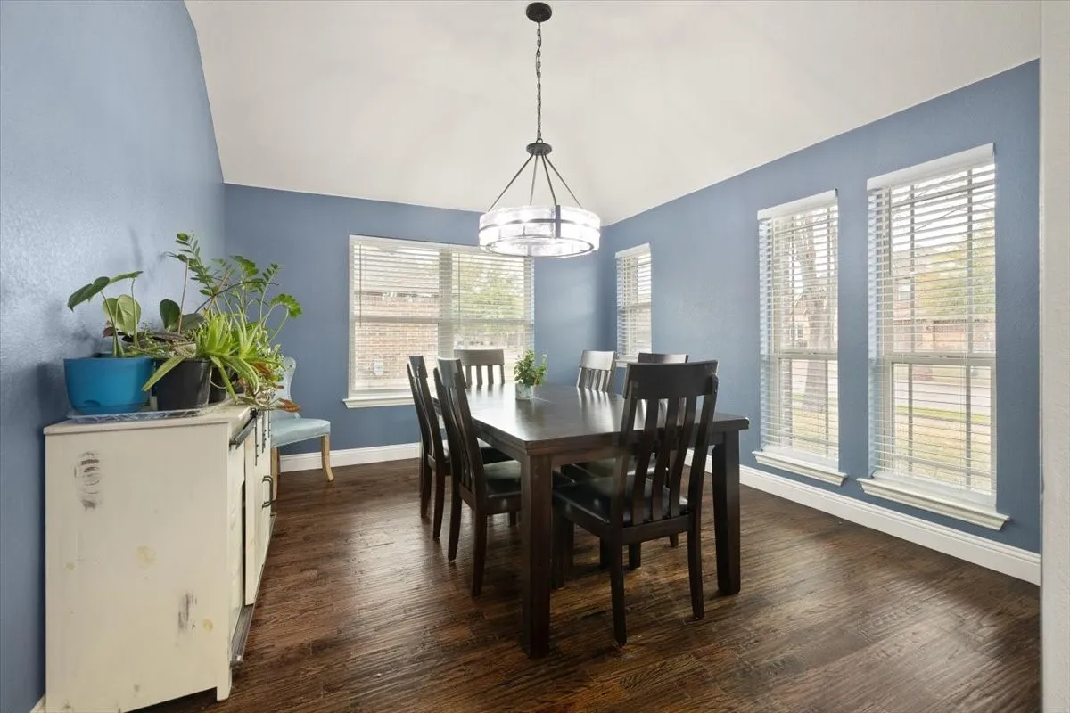 Dining room featuring dark wood-style flooring and vaulted ceiling